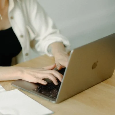 Person typing on a laptop at a wooden table
