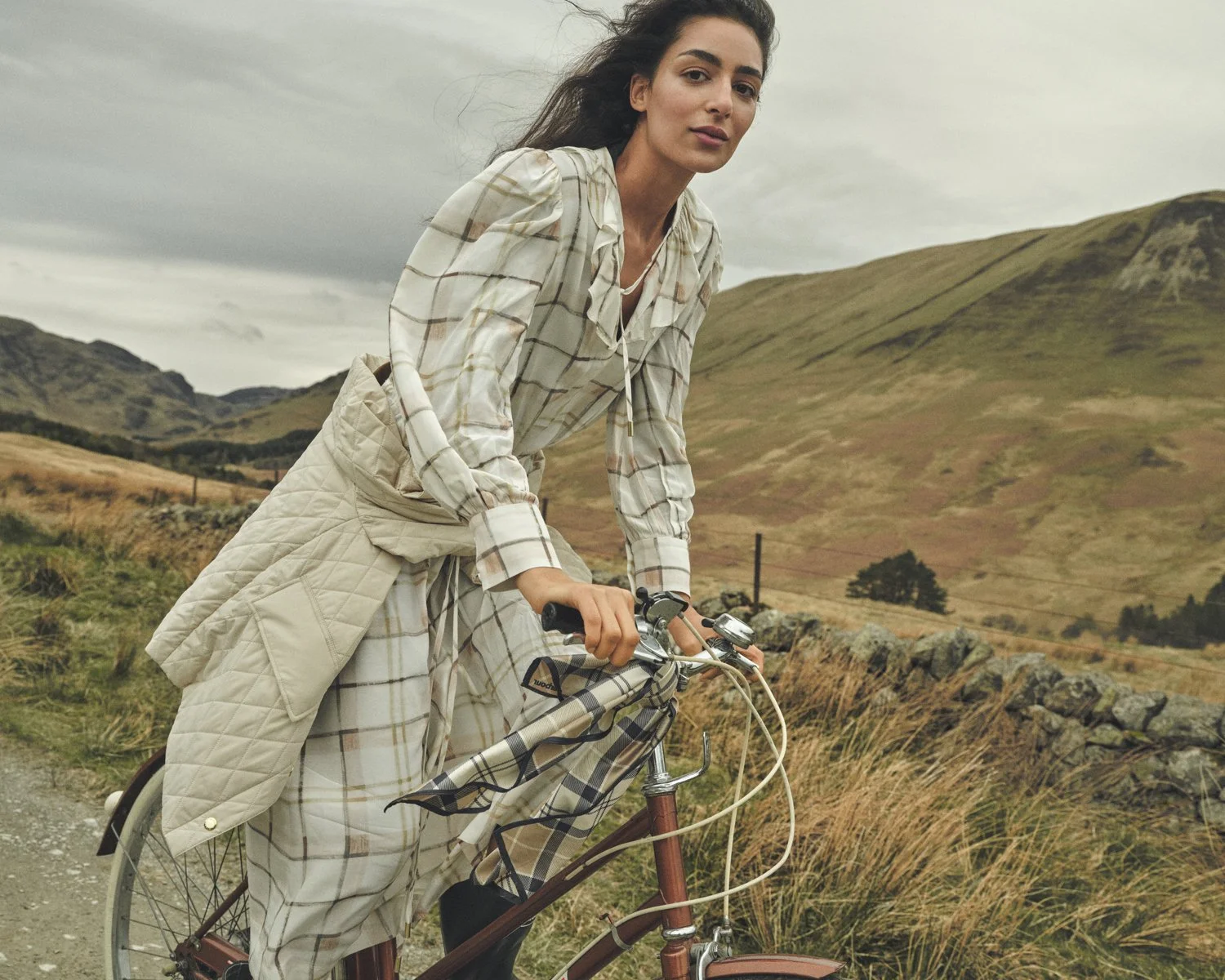 Dan Jackson photographs Nora Attal riding a bicycle through a remote Scottish Highland glen for the Barbour SS26 Campaign