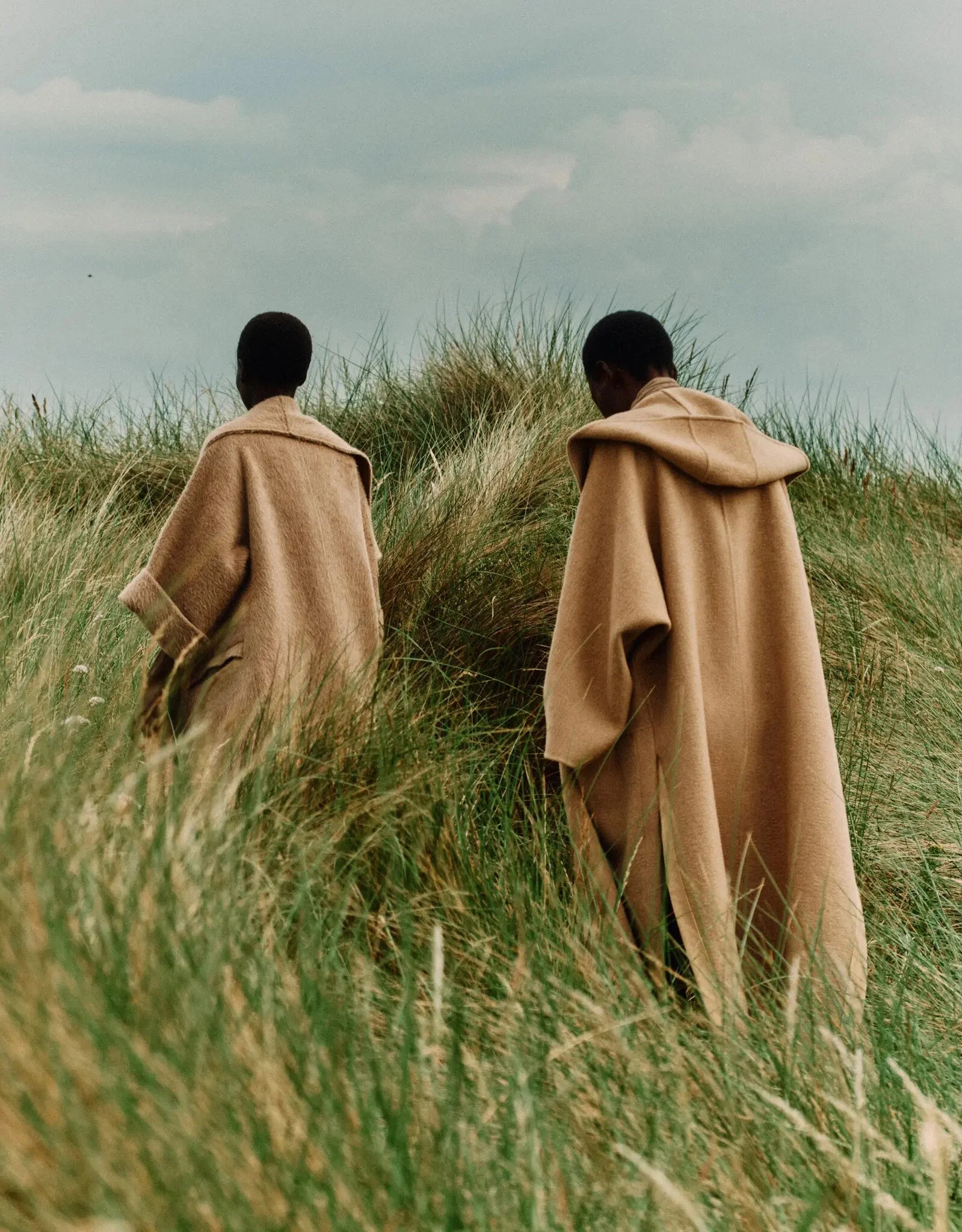 Two models dressed in Max Mara, camel coloured coats walk in long grass. 

From left: Max Mara coat, maxmara.com. Max Mara coat and Tory Burch top.

Photographed in Scotland by Jack Davison for T: The  New York Times Style Magazine.  Styled by Raphae