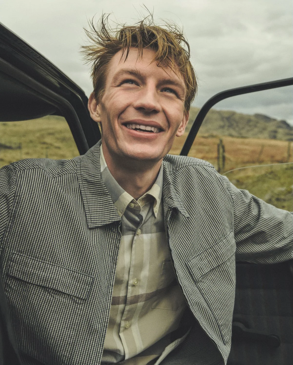 Dan Jackson photographs a male model for Barbour SS26 while exiting a classic mini car.
