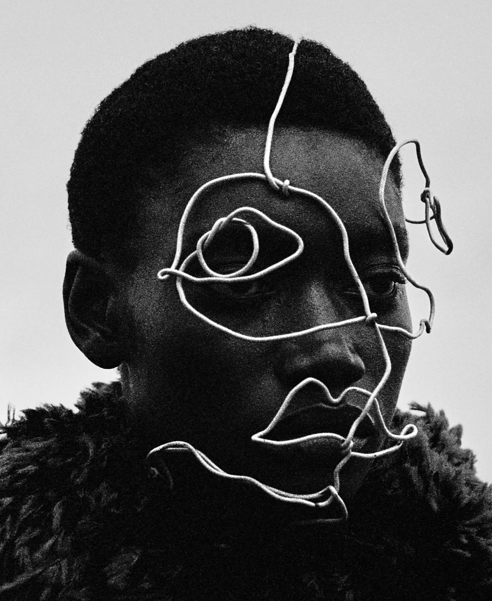 A wire sculpture is adorned on models face creating part of a striking  Editorial shoot for T: The  New York Times Style Magazine. 

Model wears Givenchy by Sarah Burton top. 

Photograph by Jack Davison. Styled by Raphael Hirsch. Local Production an