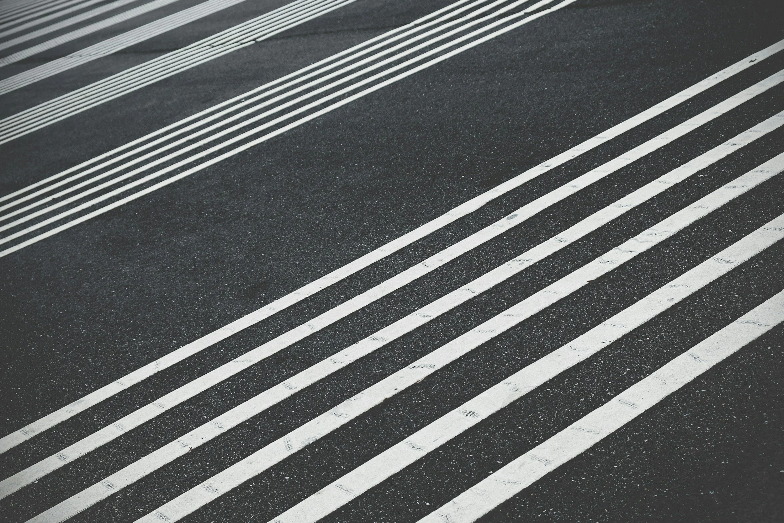 Black asphalt road with white painted lane markings and textured surface.