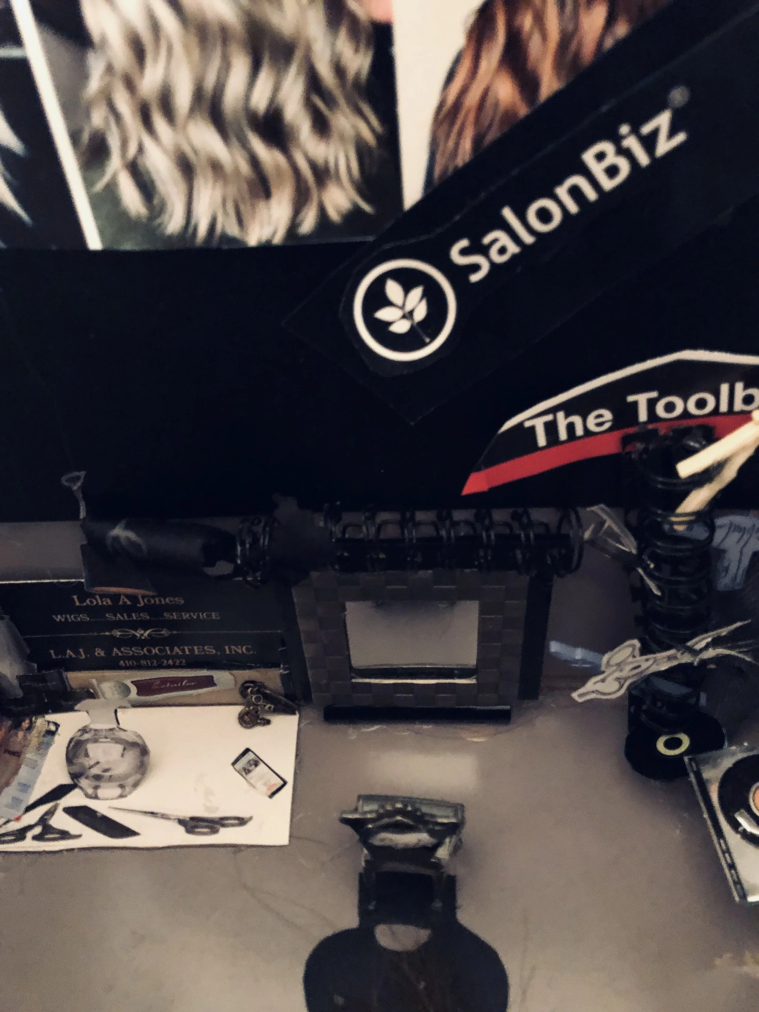 Desk with various items including a mirror, business cards, a photo of a woman's hair, a hairbrush, and miscellaneous objects.