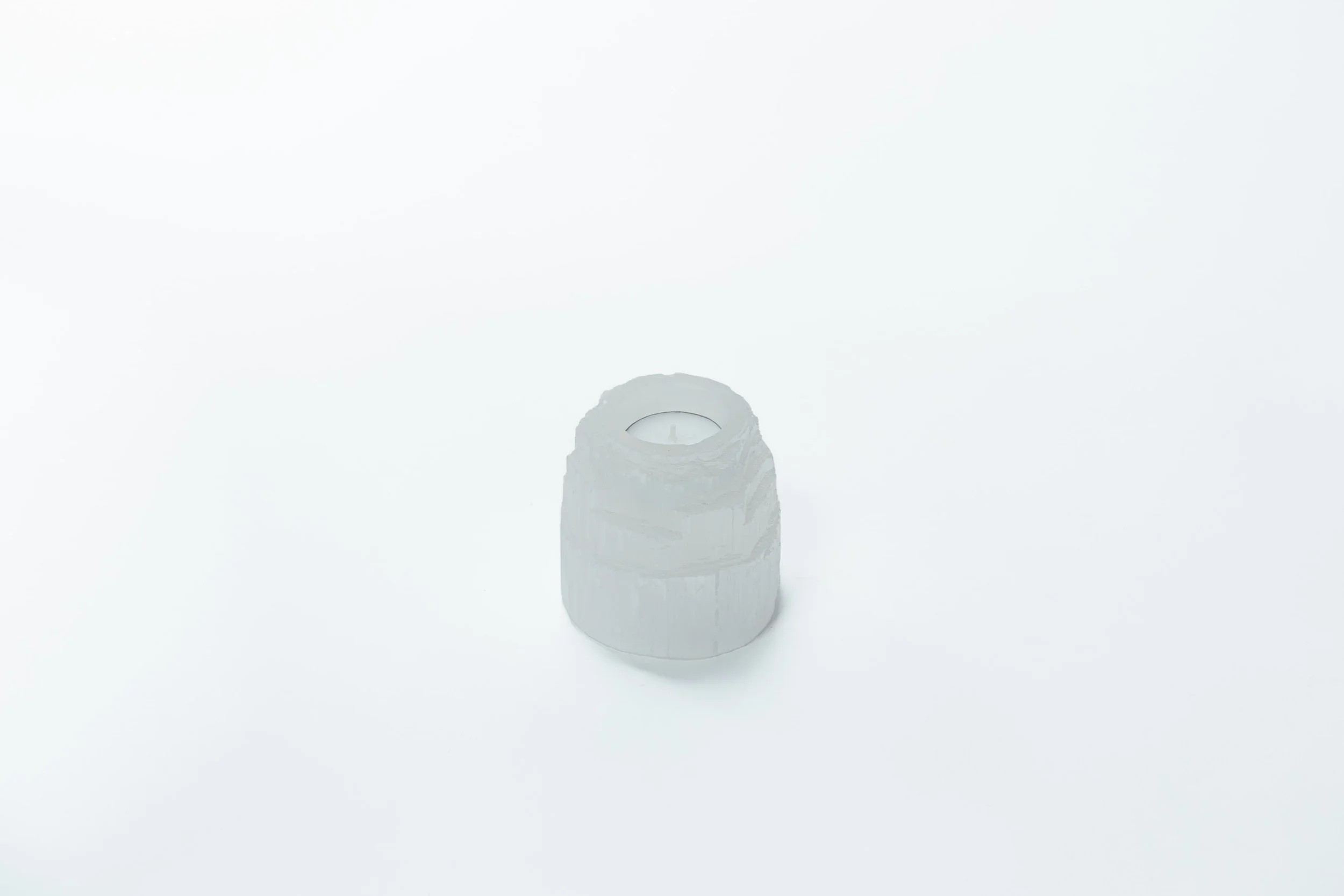 Witte kaars in een houten houder op een witte achtergrond.