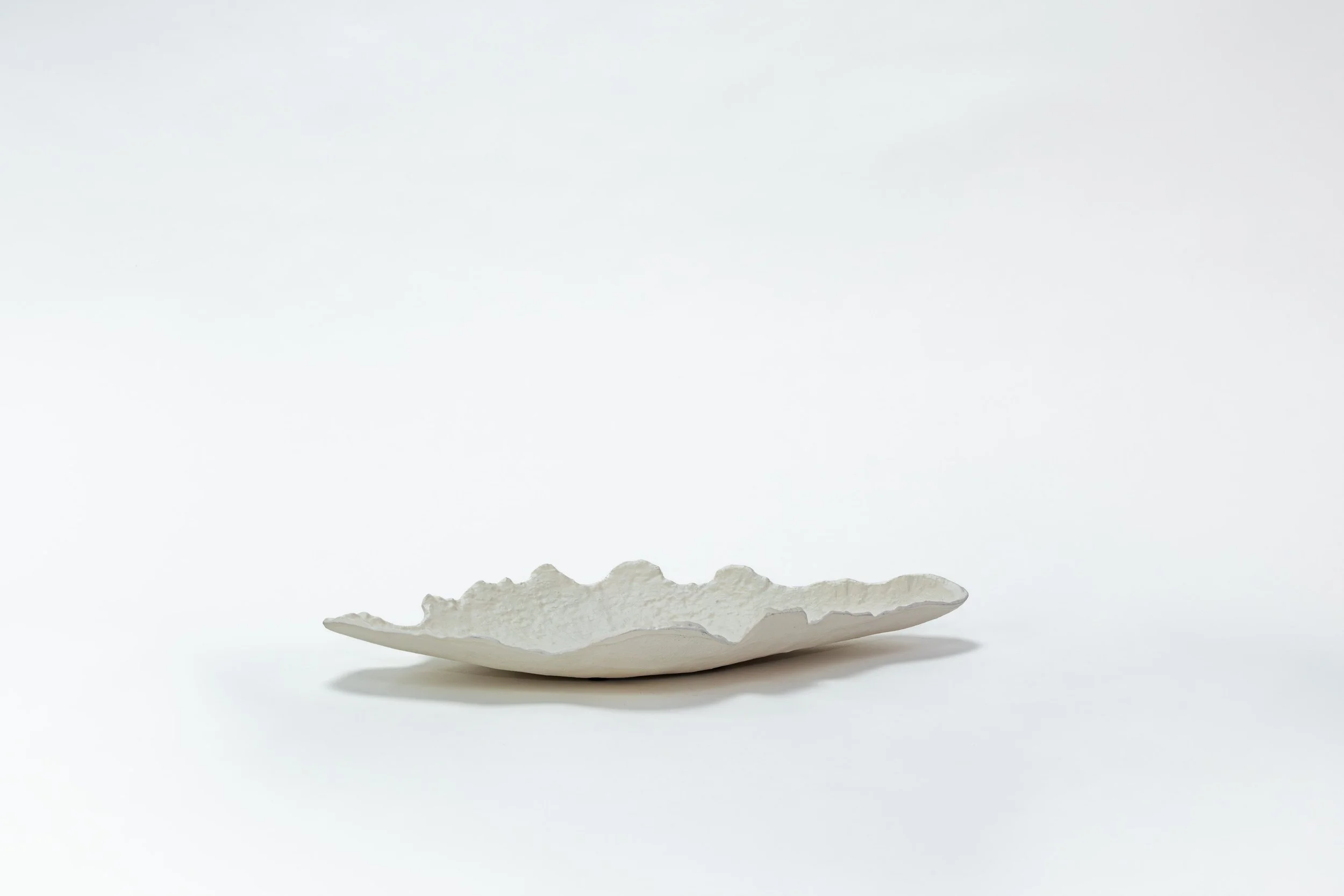 Witte onregelmatig gevormde keramieken schaal op een witte achtergrond
