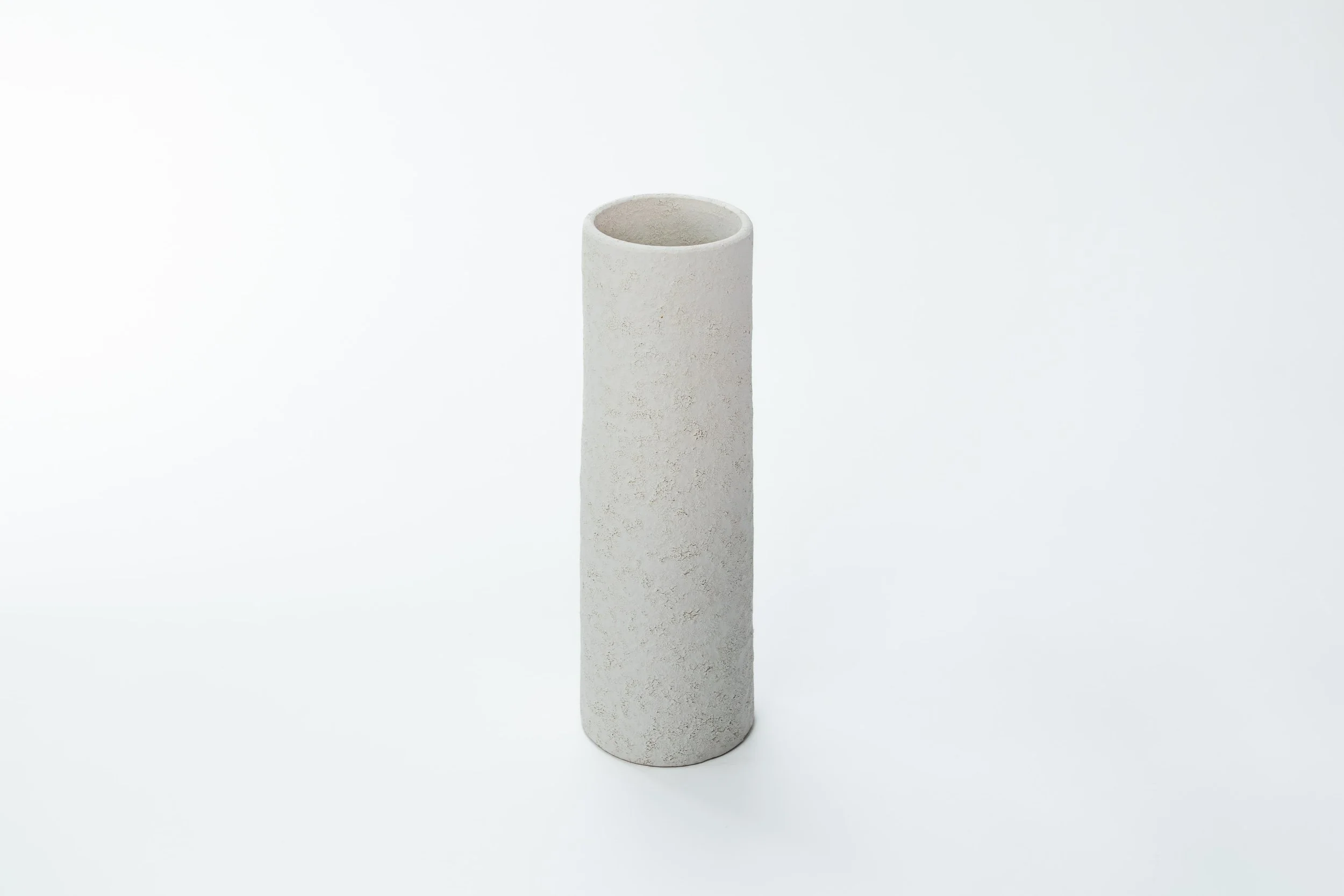 Een witte, cilindervormige muurpot van klei of keramiek, geplaatst op een witte achtergrond.