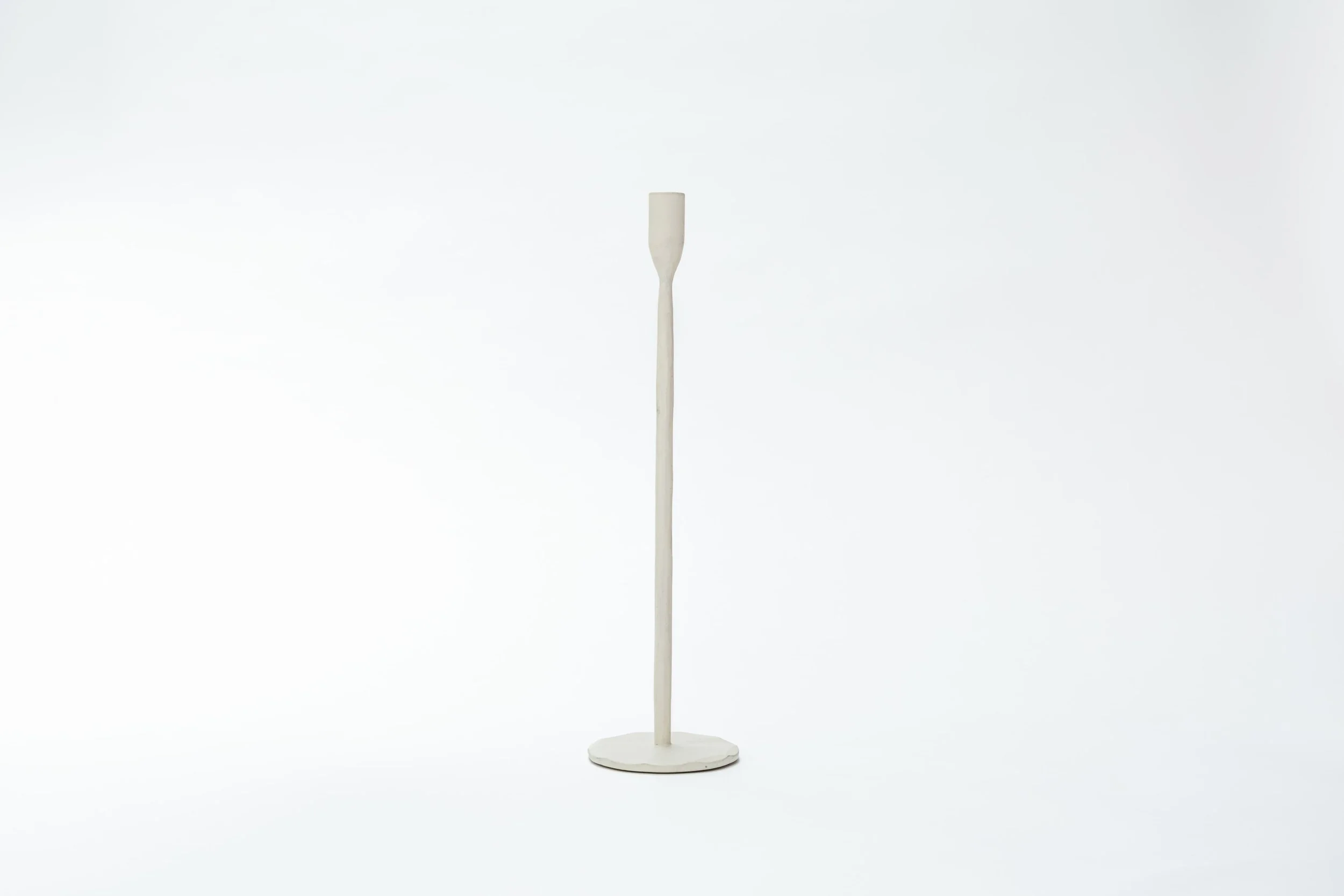 Een witte kaars met een lange, dunne kaarsstok en een ronde, platte voet