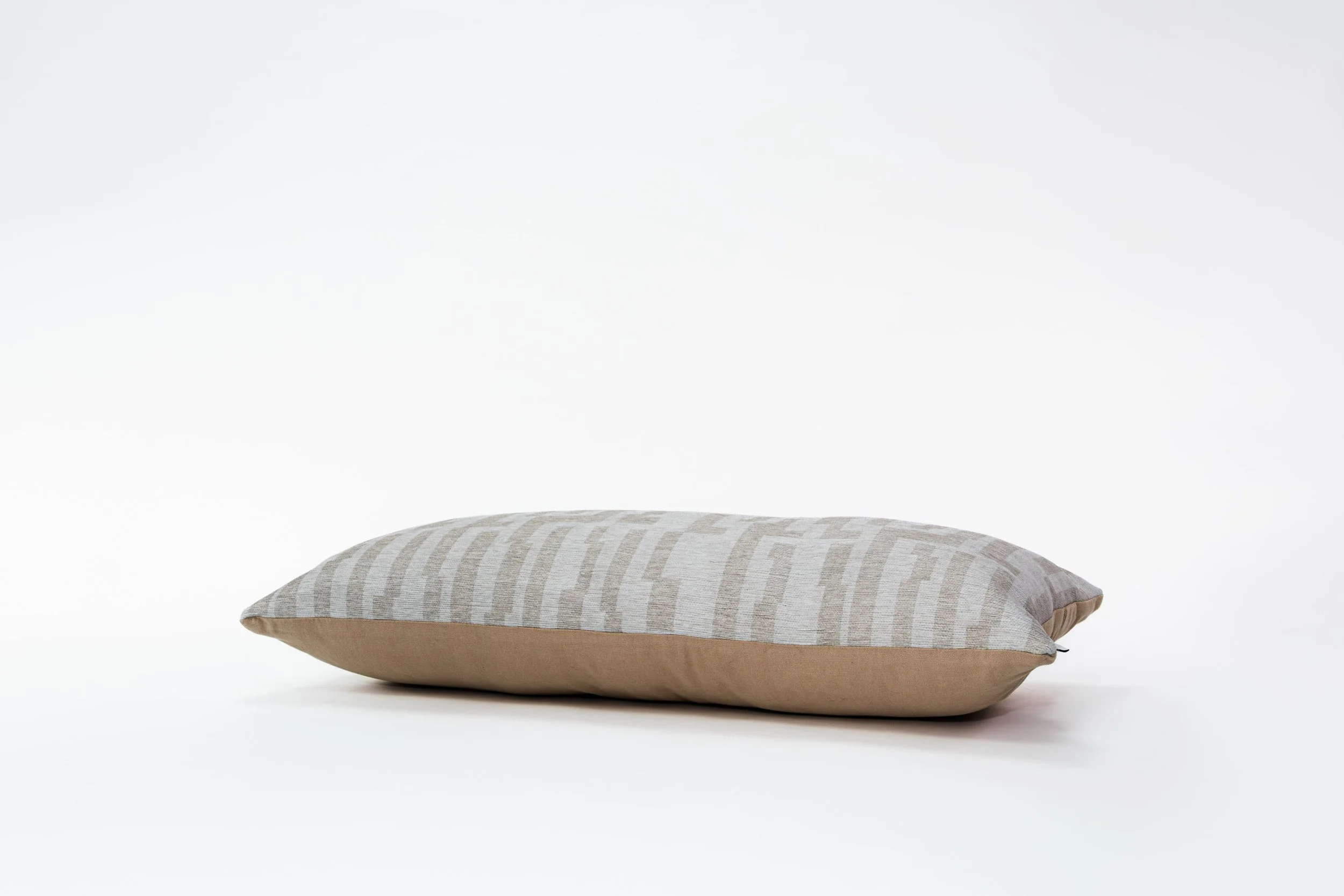 Lange kussen met beige en grijs gestreept patroon op een witte achtergrond.