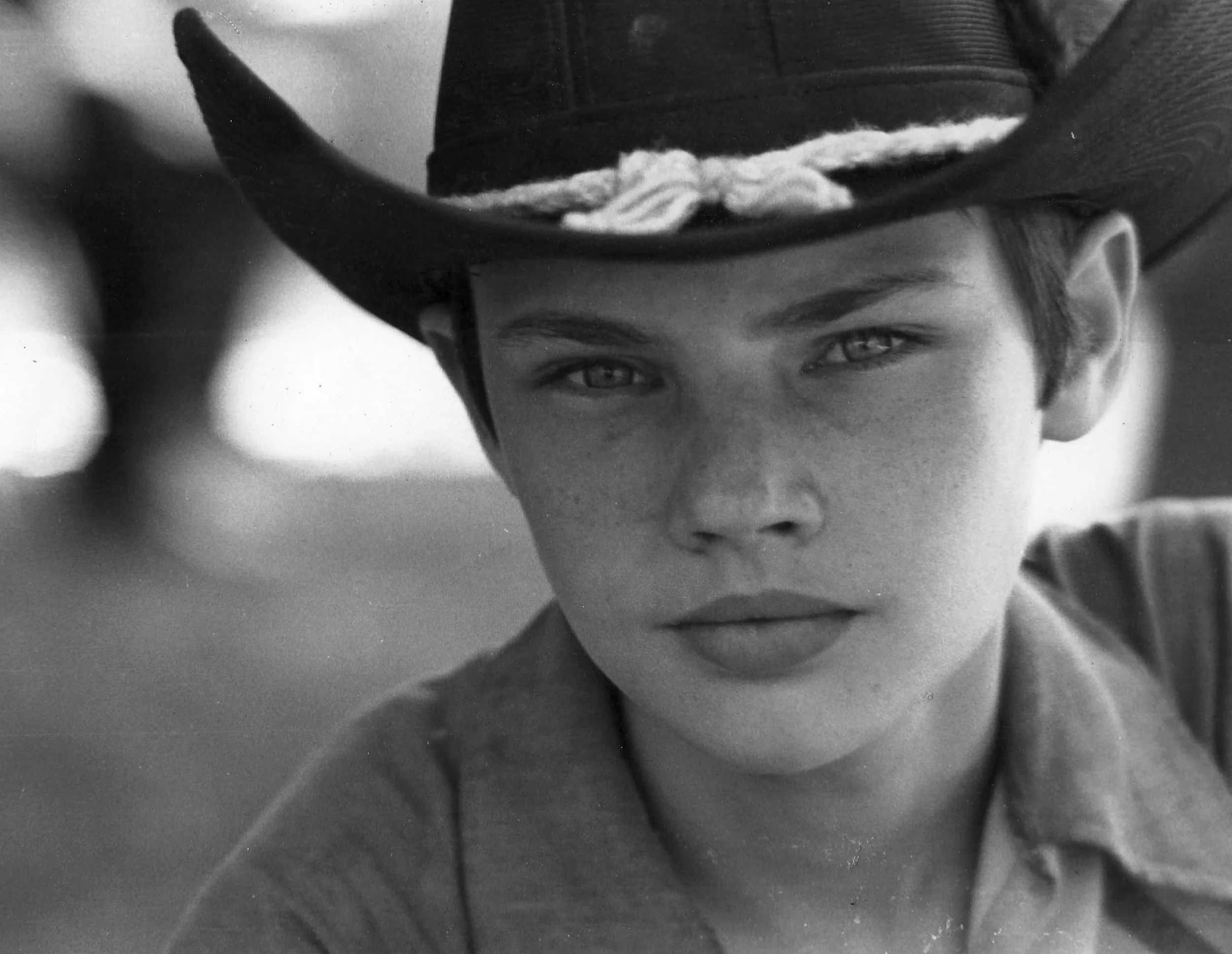Black and white close-up photo of a young man wearing a cowboy hat, with intense eyes and serious expression.