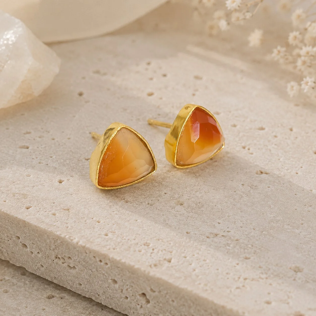 Orangefarbene Sardonyx Edelstein Ohrringe auf heller Naturstein-Schmuckplatte dekorativ arrangiert