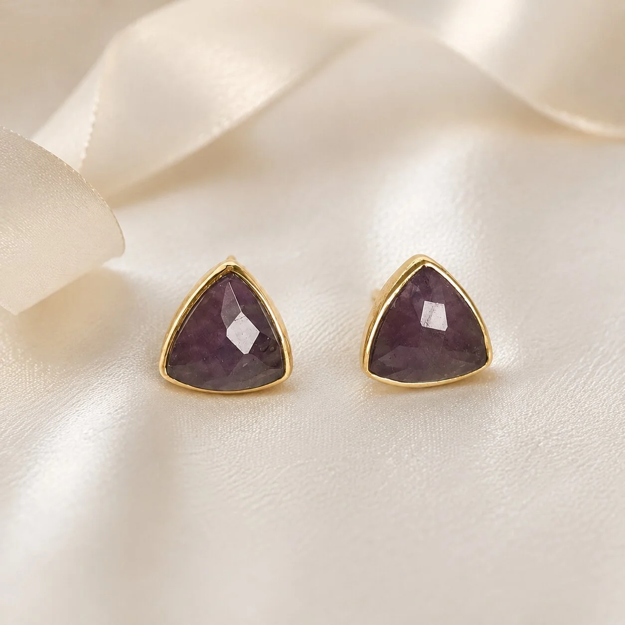 Amethyst Geburtsstein Ohrringe auf hellem Satinstoff arrangiert
