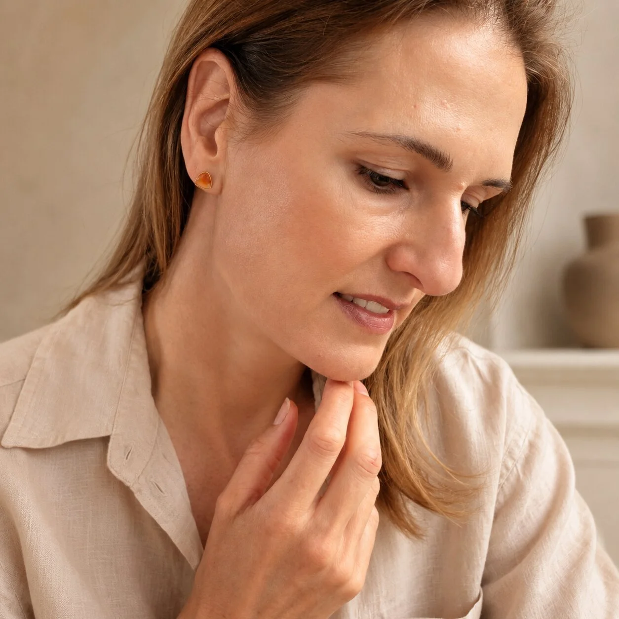 Stilvolles Model präsentiert vergoldete Ohrringe mit orangefarbenem Sardonyx für einen eleganten Alltagslook