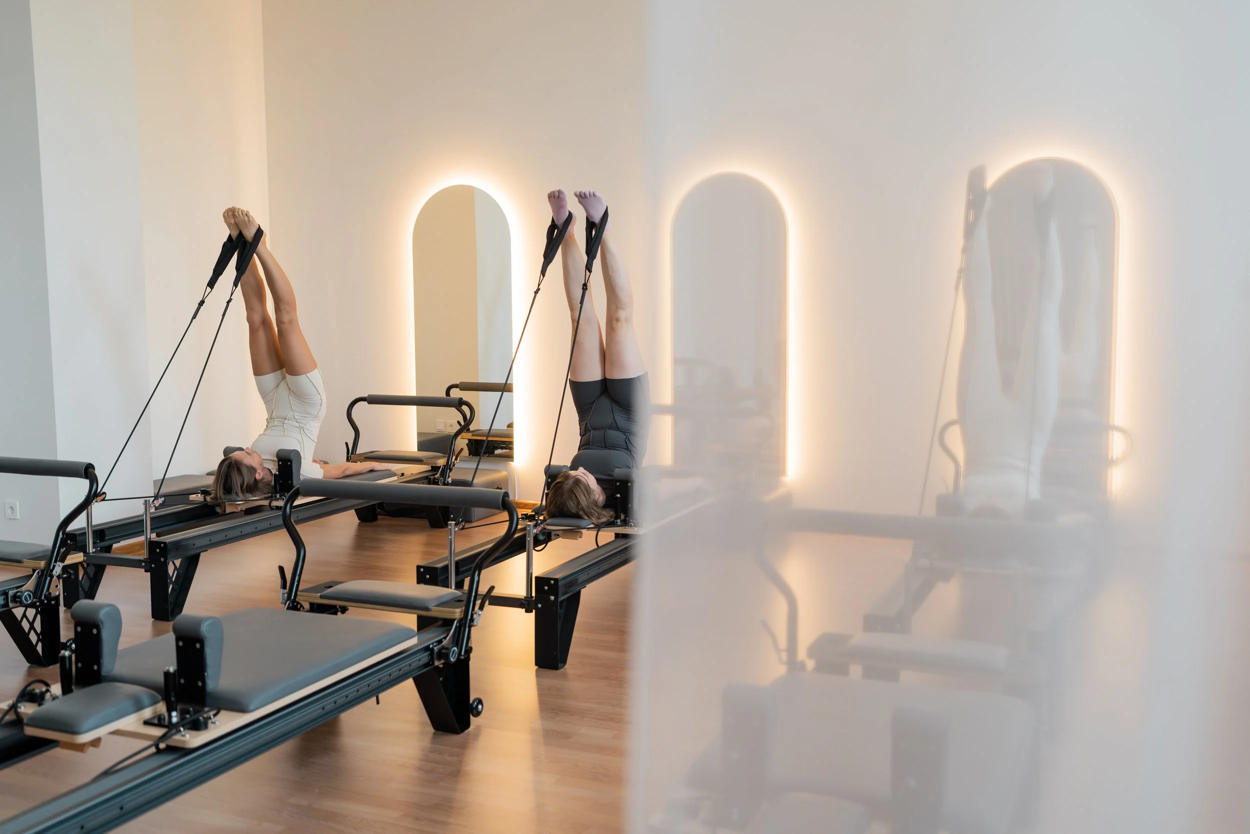 Salle de pilates moderne avec équipements Reformer et miroirs rétroéclairés dans un espace bien-être rénové en Drôme