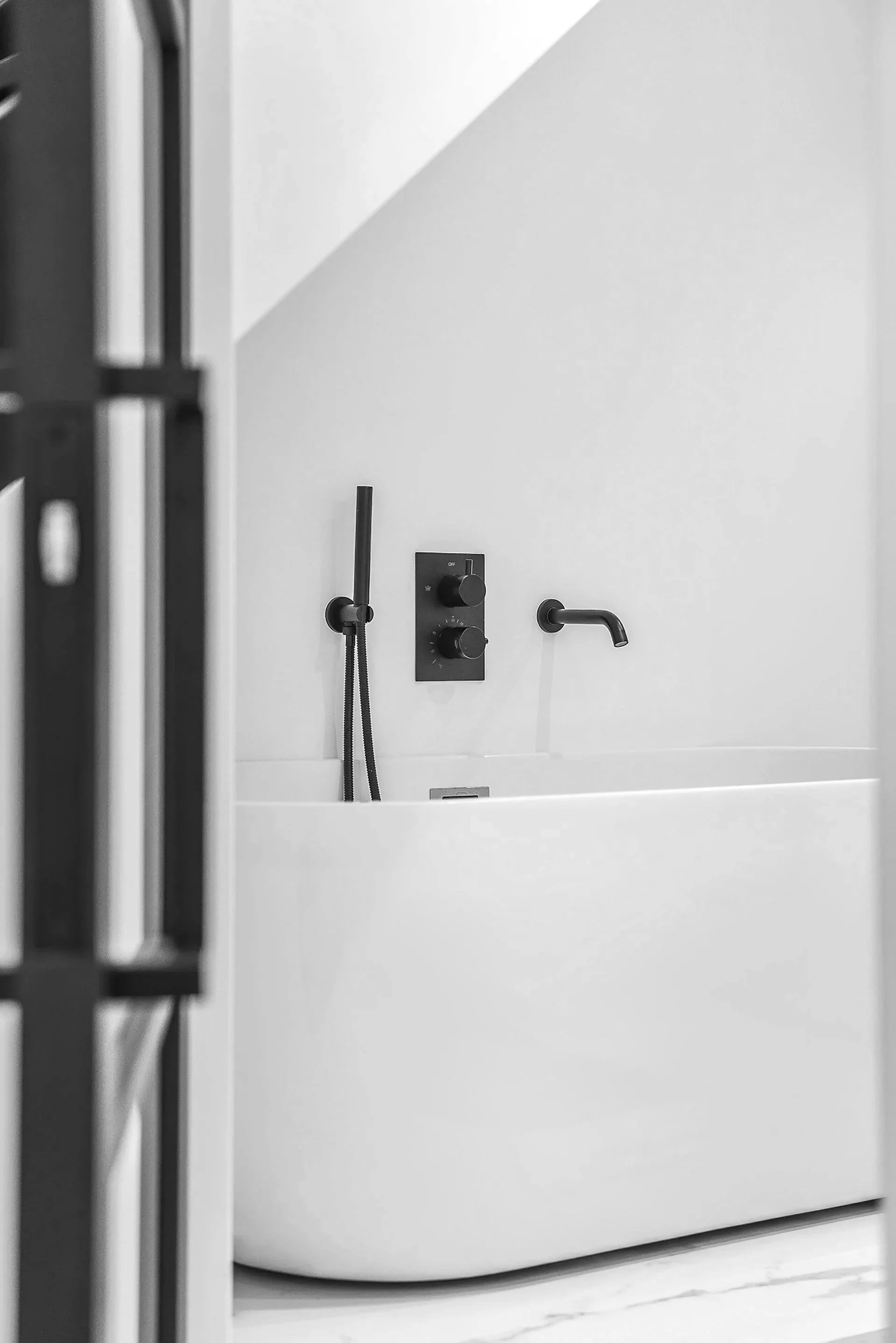 Salle de bain rénovée aux lignes épurées avec robinetterie noire et finitions soignées après rénovation complète.