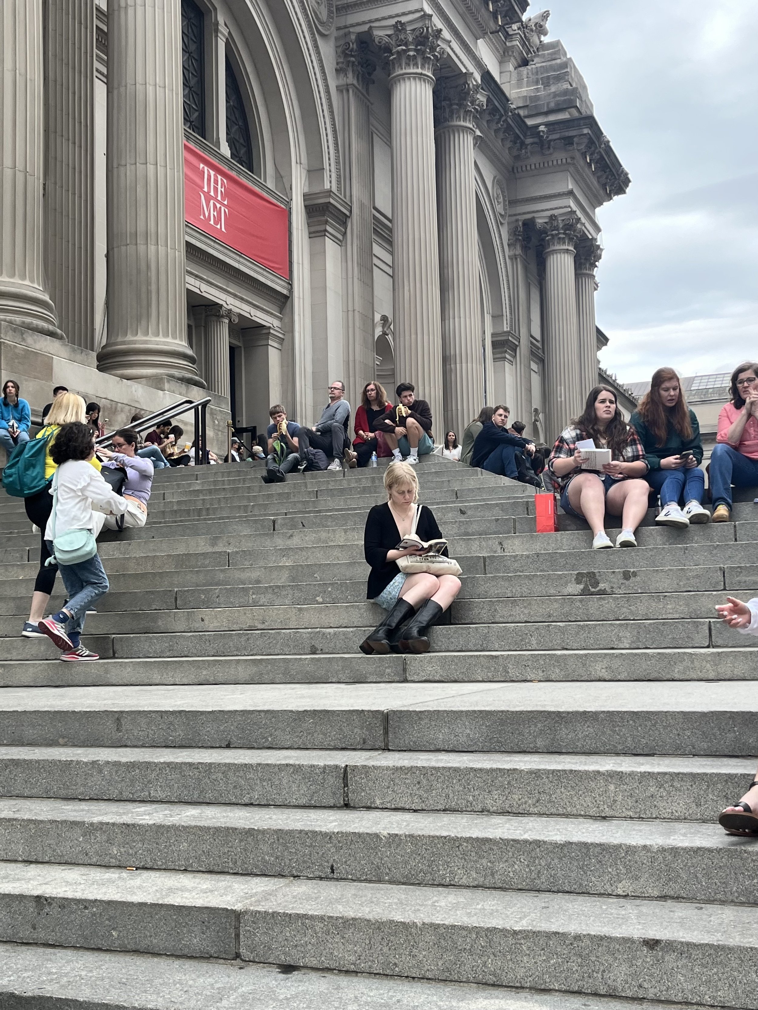Emily Morgan reading on the steps of the Metropolitan Museum of Art.