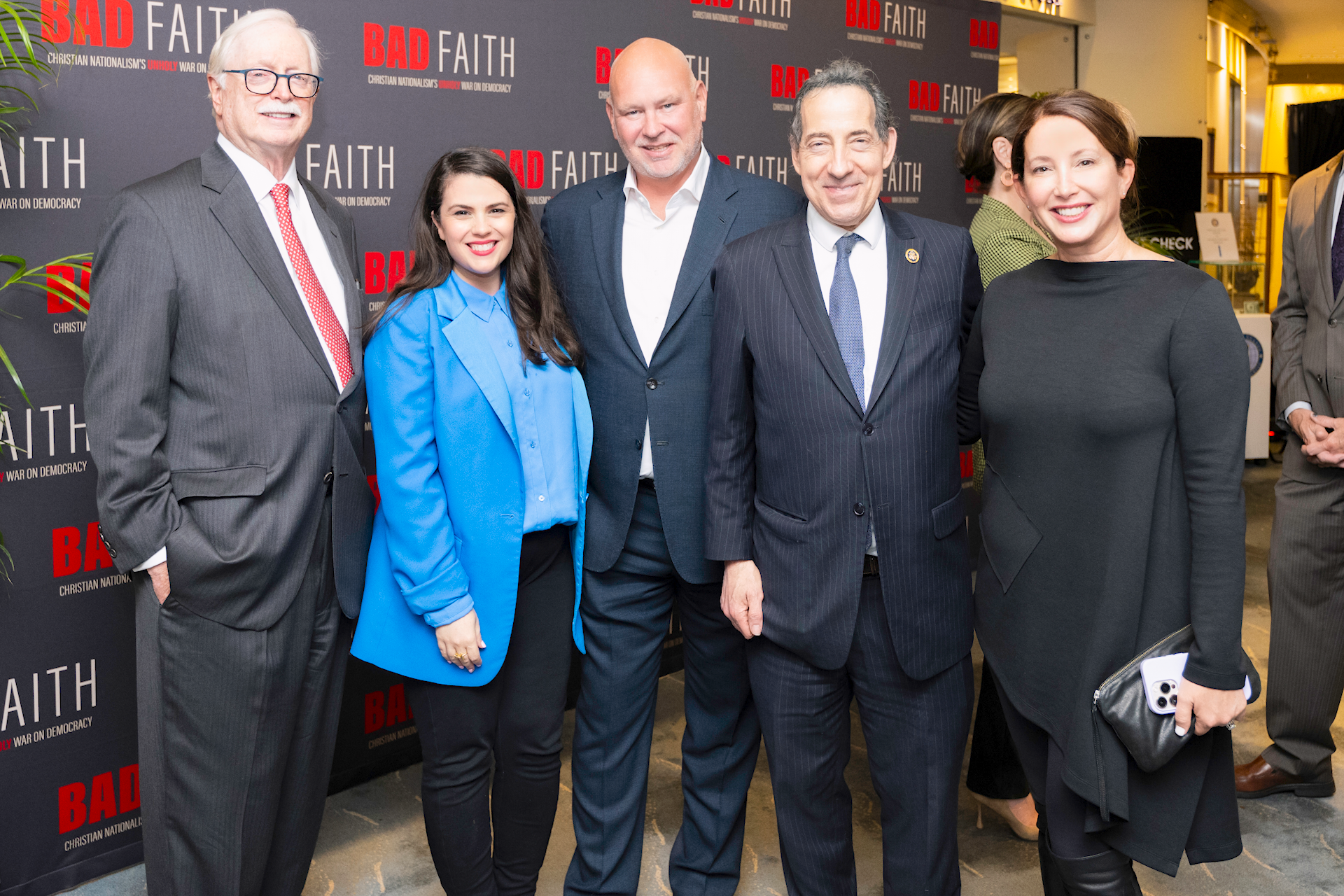 Group of five people, three men and two women, standing together at a Christian Nationalism event with a backdrop reading 'BAD FAITH' and 'Christian Nationalism's Unholy War on Democracy.' They are dressed in professional attire, smiling for the photo.