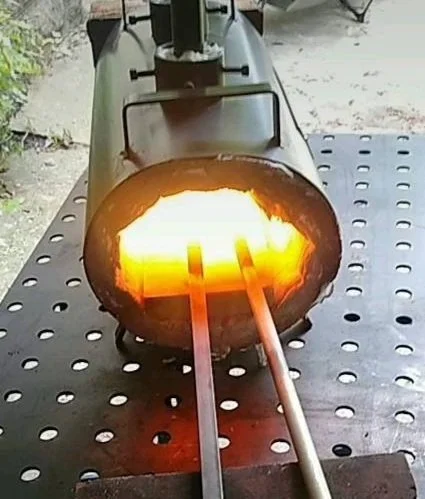 A large metal rocket engine with bright orange flames and exhaust coming out of the nozzle, mounted on a metal stand.