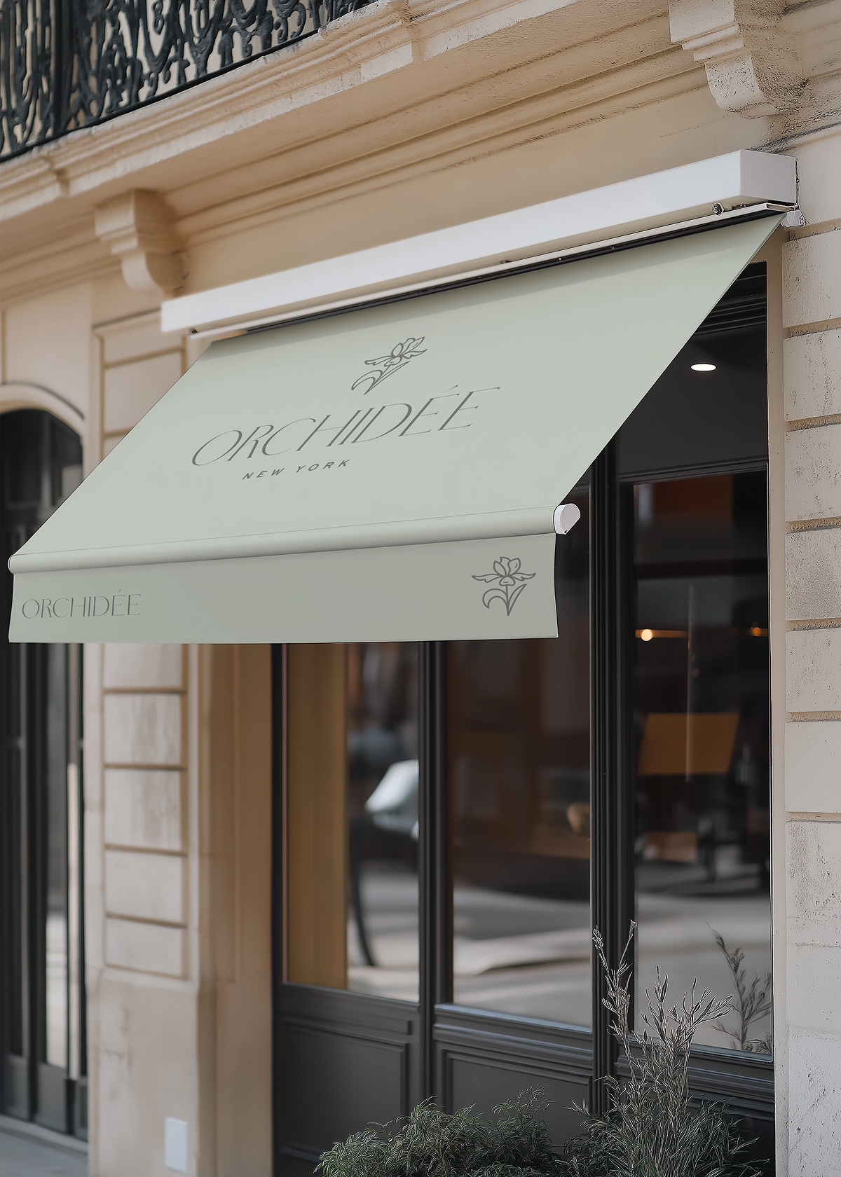 Exterior view of a storefront with a light green awning displaying the name 'Orchidée New York' and floral logo, with large black-framed windows and houseplants in front.
