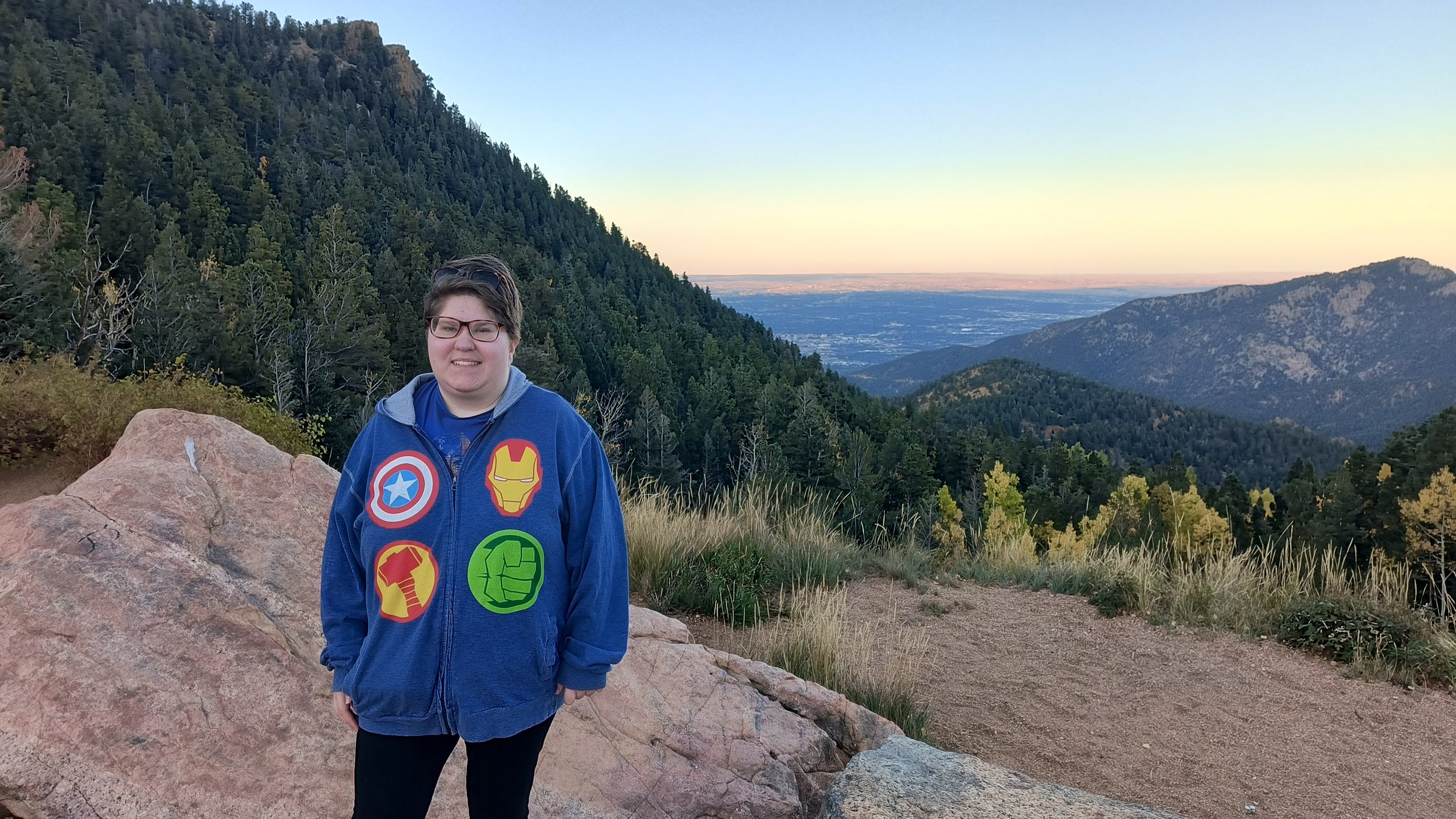 Kylie Walden standing in the Colorado mountains smiling brightly. A neurodivergent improv student who found confidence and belonging through Peak Improv’s Gentle Improv program.