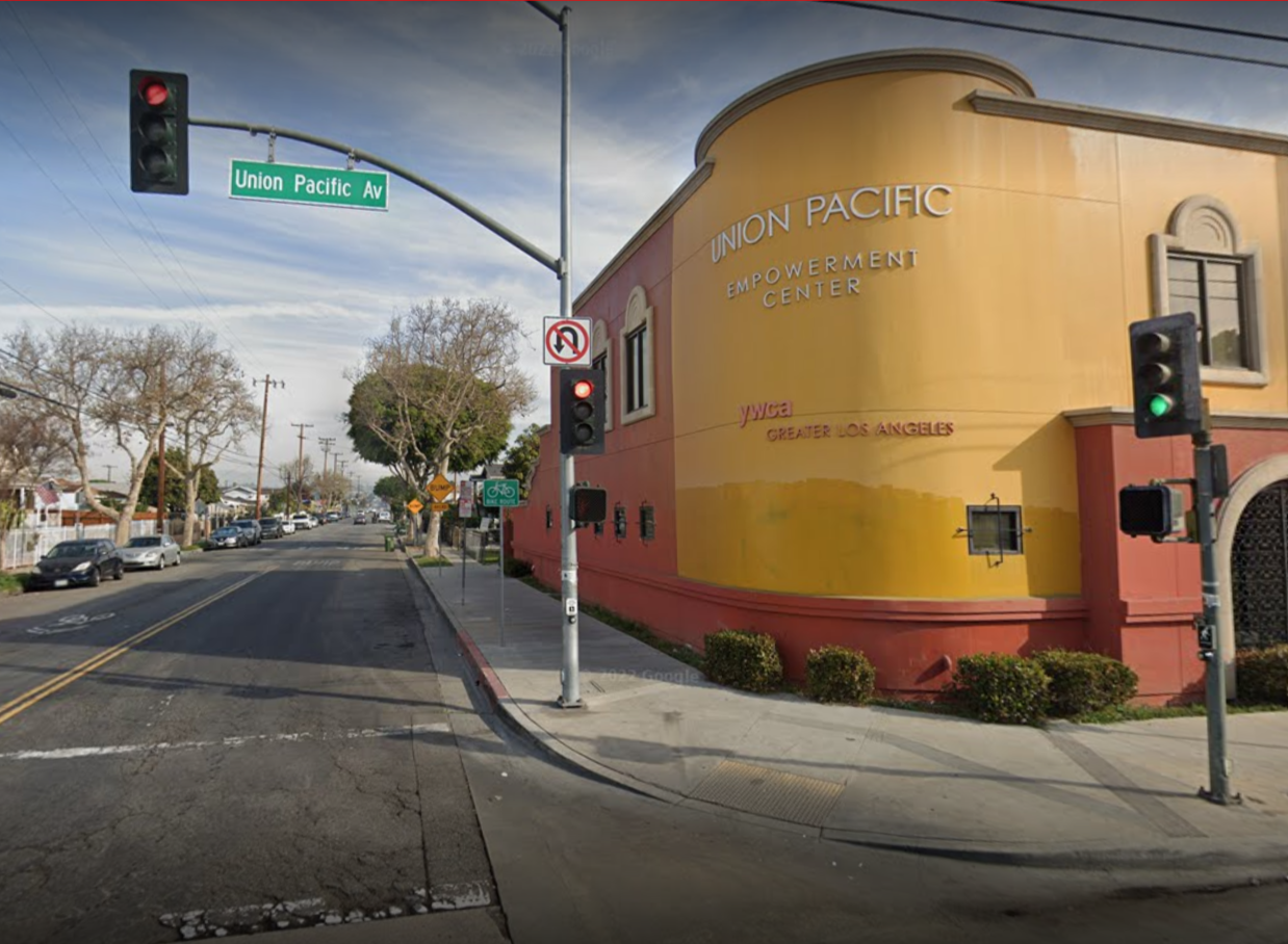 Street view of Union Pacific Avenue with traffic lights, a building on the corner labeled 'Union Pacific Empowerment Center' and 'YWCA Greater Los Angeles,' trees lining the sidewalk, and parked cars along the street.