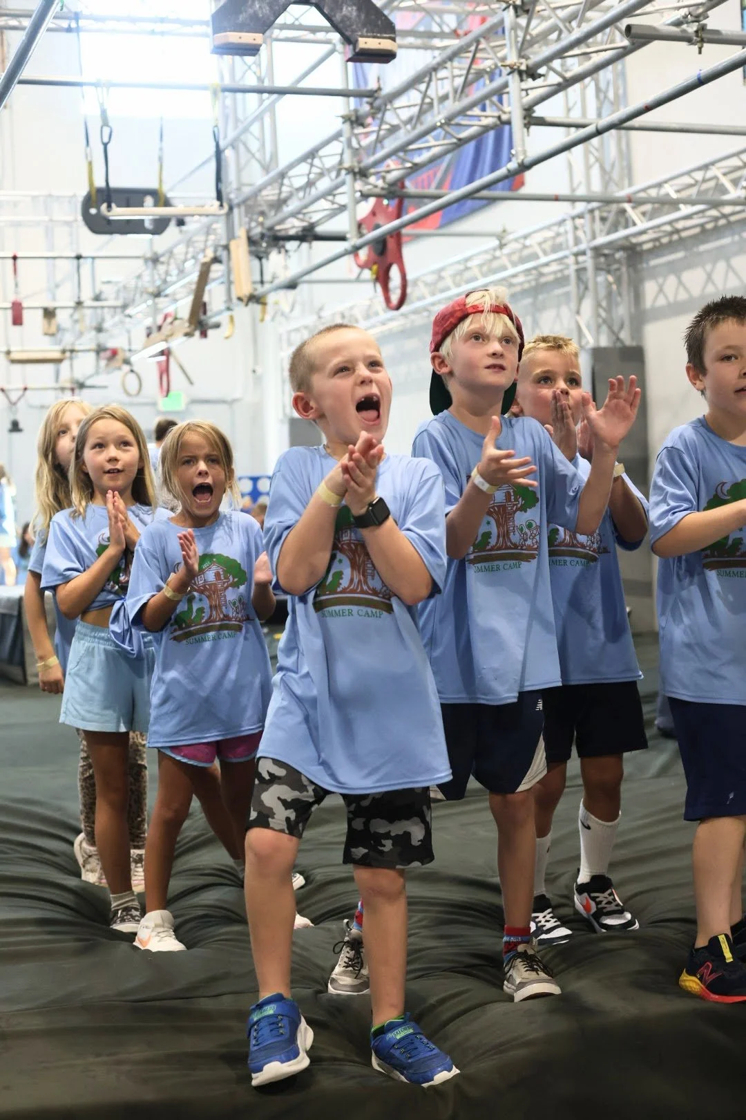 Cheering kids and students celebrating on the mat during a school field trip at Ark Ninja Warrior gym.