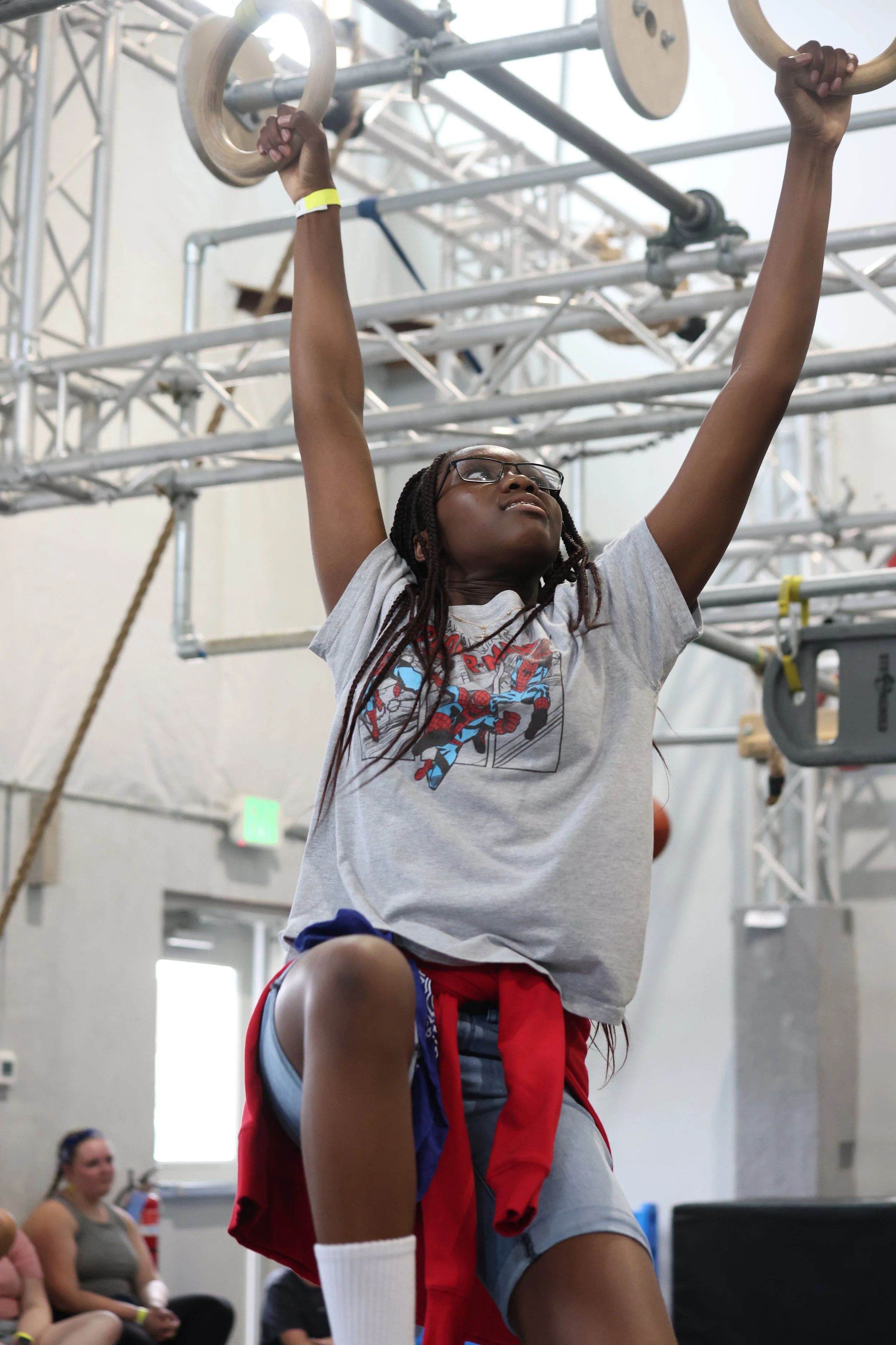 Student tackling a gymnastics ring obstacle during a group field trip at Ark Ninja Warrior training facility.