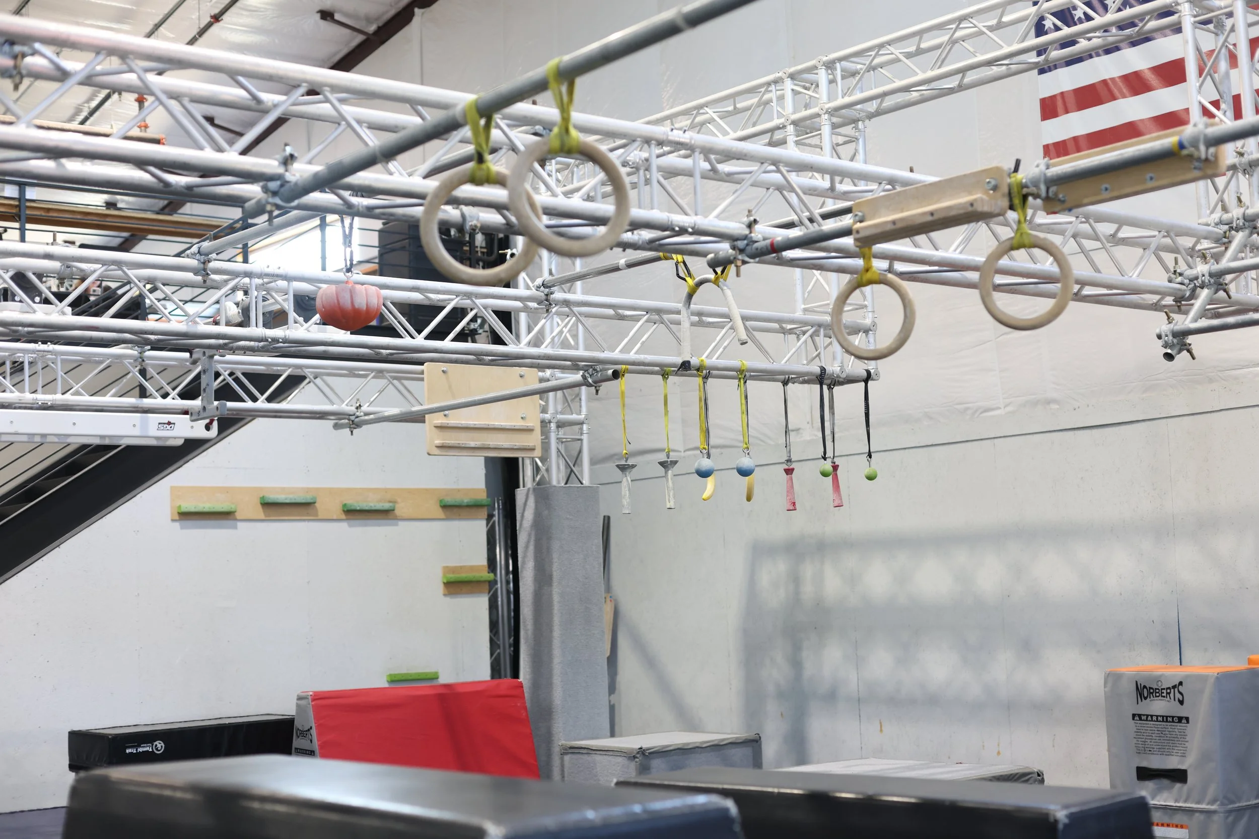 ARK Ninja Longmont Ninja Warrior gym obstacle course with hanging rings, climbing obstacles, and padded landing mats