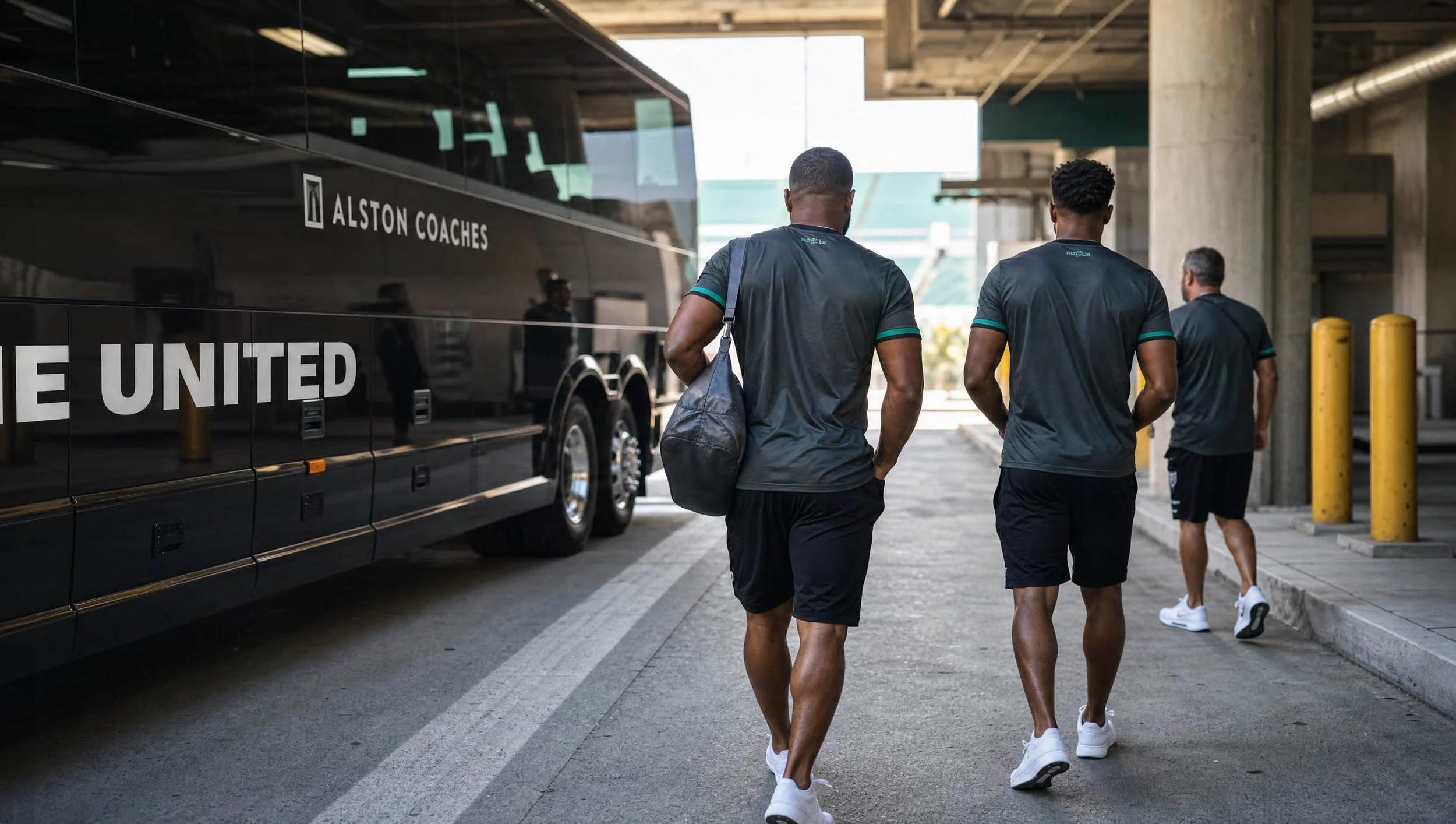 Three men wearing black athletic clothes walking past a black bus labeled 'Alston Coaches' at a bus station or terminal.