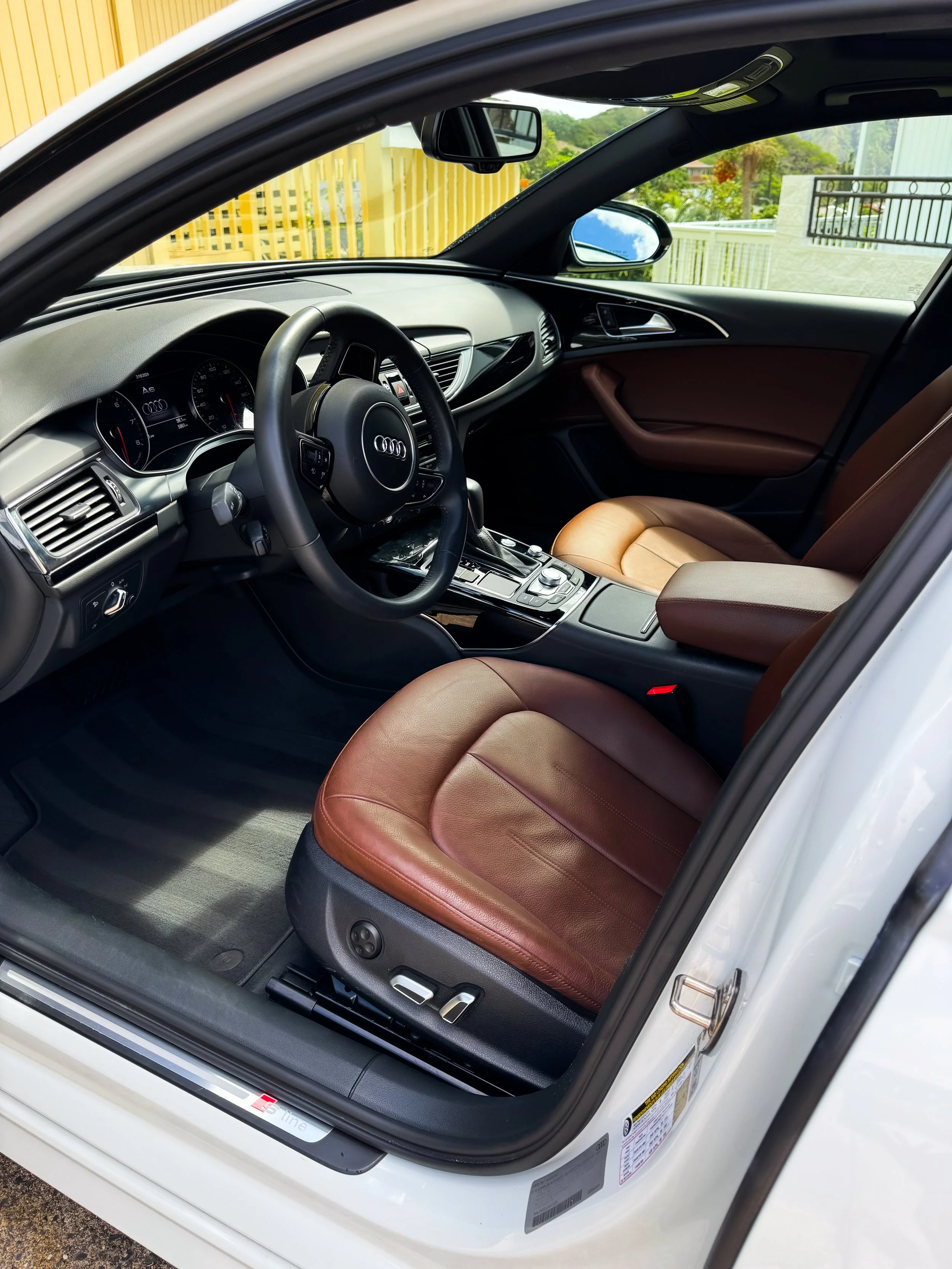 Audi car interior with brown leather seats and black dashboard, showing steering wheel and controls.