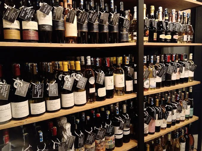 Shelves stocked with various bottles of wine at a store, each with a black tag attached.