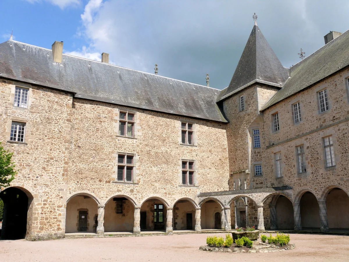 A stone castle with multiple arched entrances and rectangular windows, featuring a tall tower with a pointed roof, located in a courtyard with a well and some greenery.