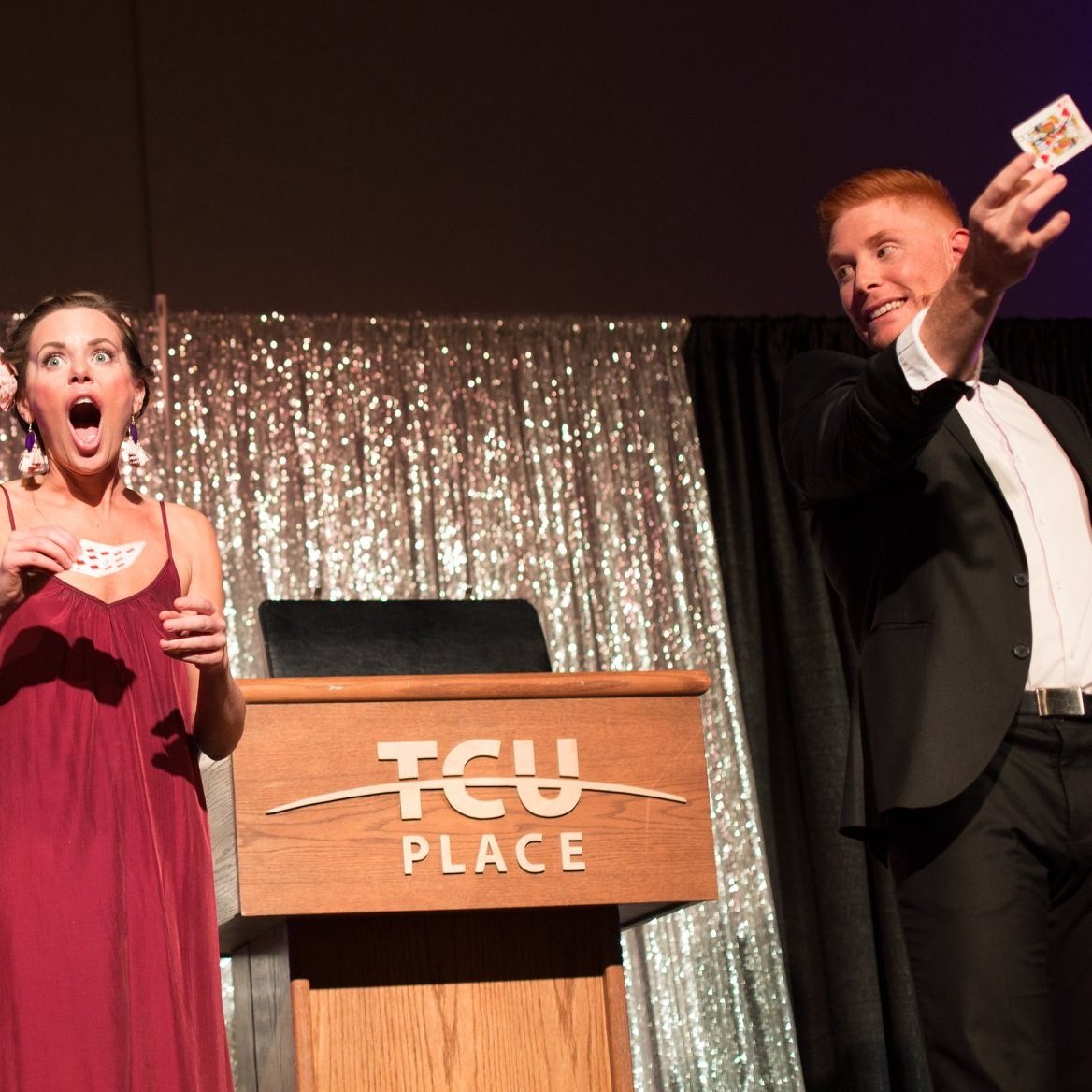  A woman is surprised at Matt Gore's magic show, showcasing a card trick on stage 