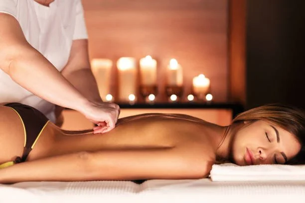 Frau erhält eine Massage im Spa, im Hintergrund Kerzen.