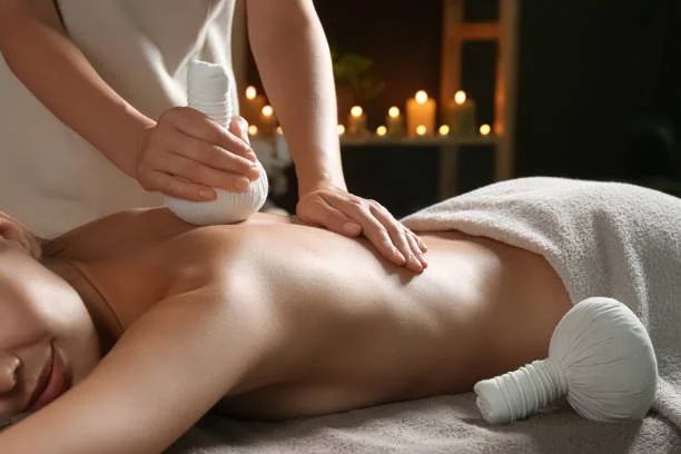 Person erhält eine Massage mit einem Gua sha Stein im Spa-Umfeld bei Kerzenlicht.
