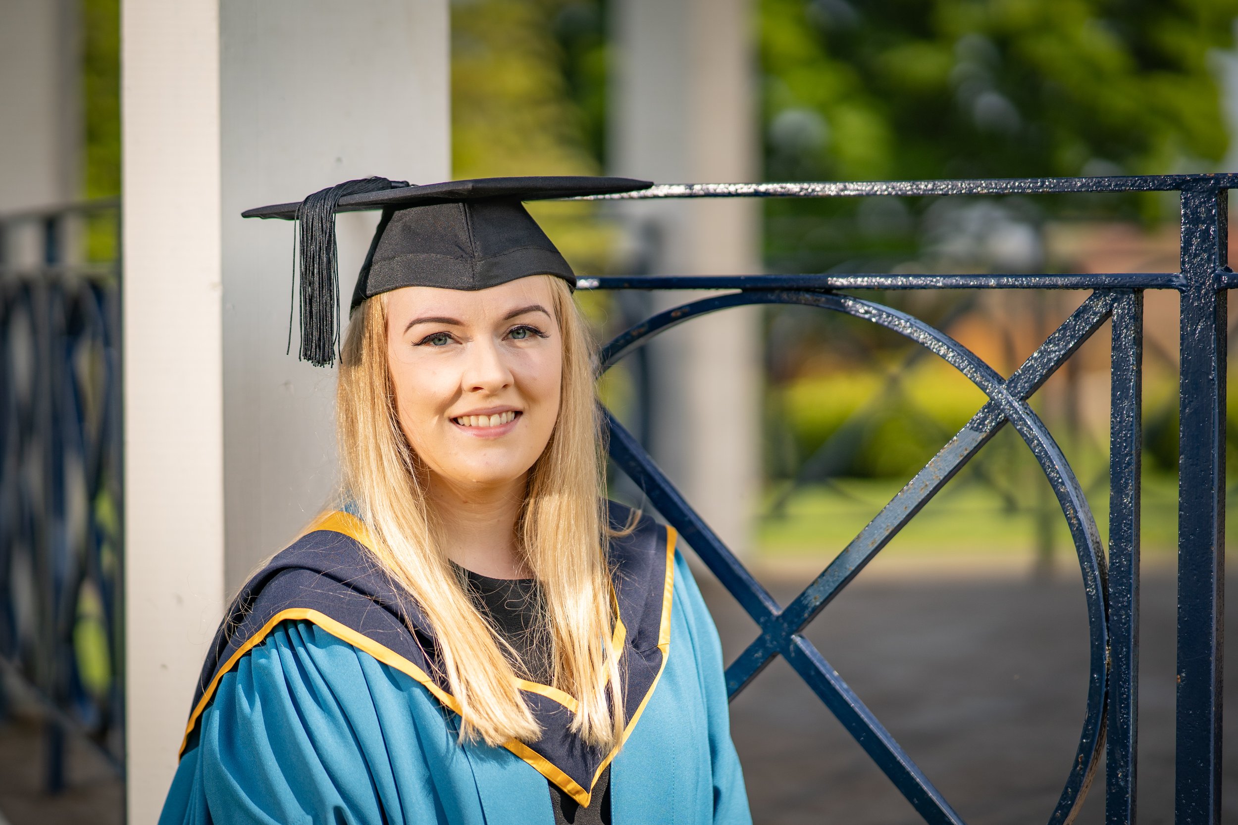 Me in graduation cap and blue gown in front of a bandstand.