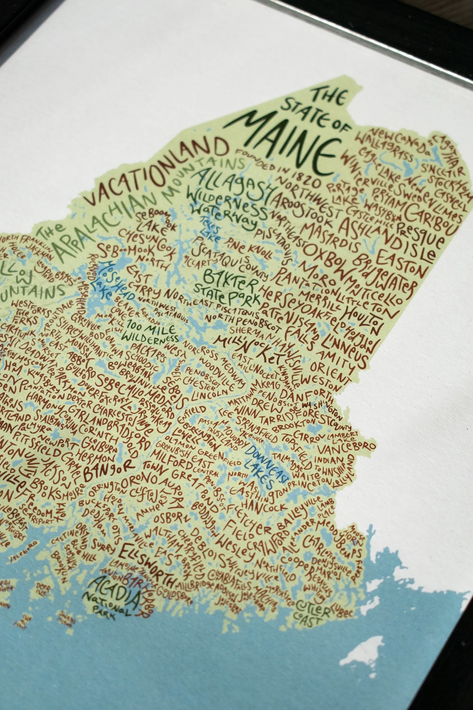 Colorful illustrated map of Maine with towns, lakes, and geographic features labeled in various colors.