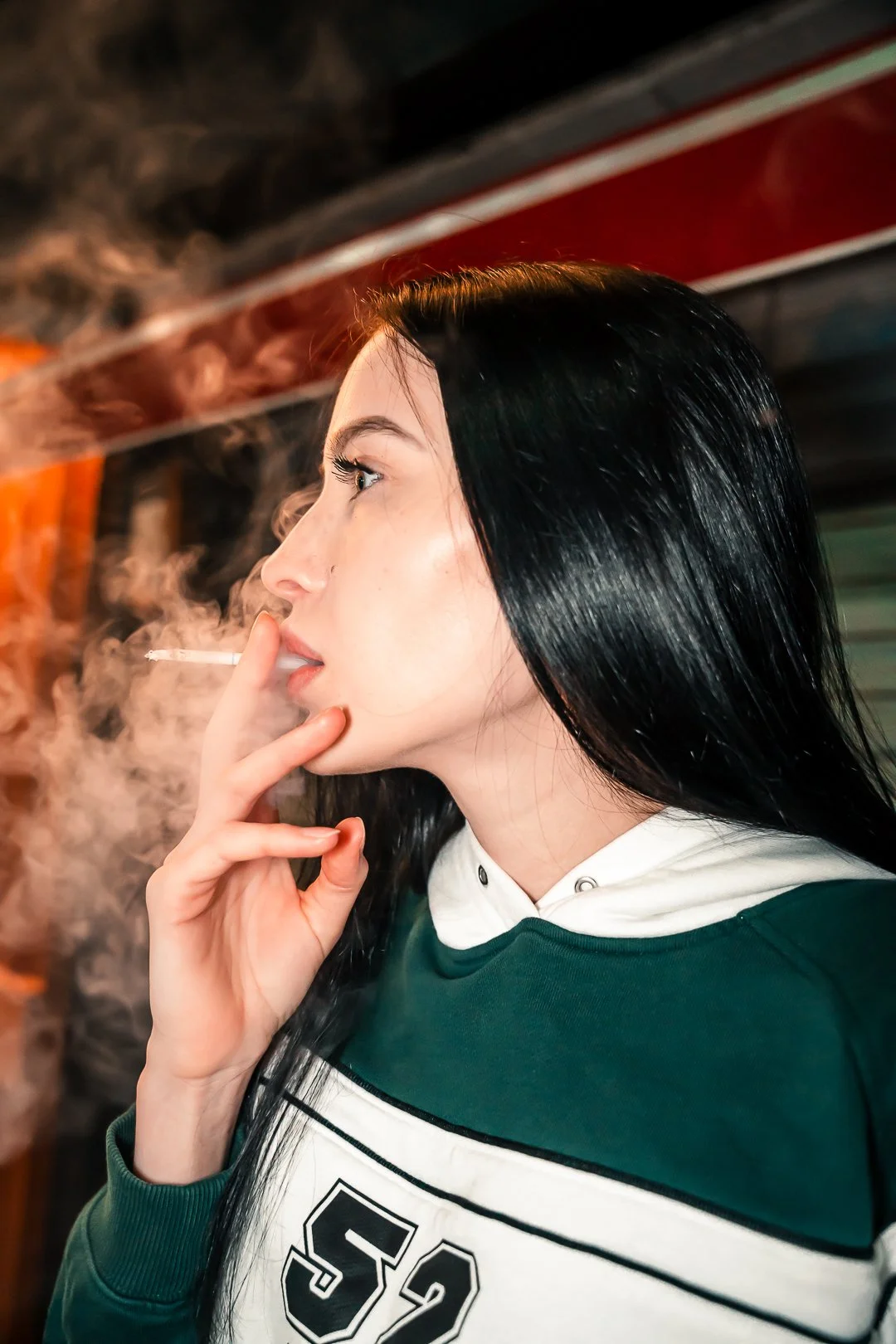 A woman with long black hair smoking a cigarette.