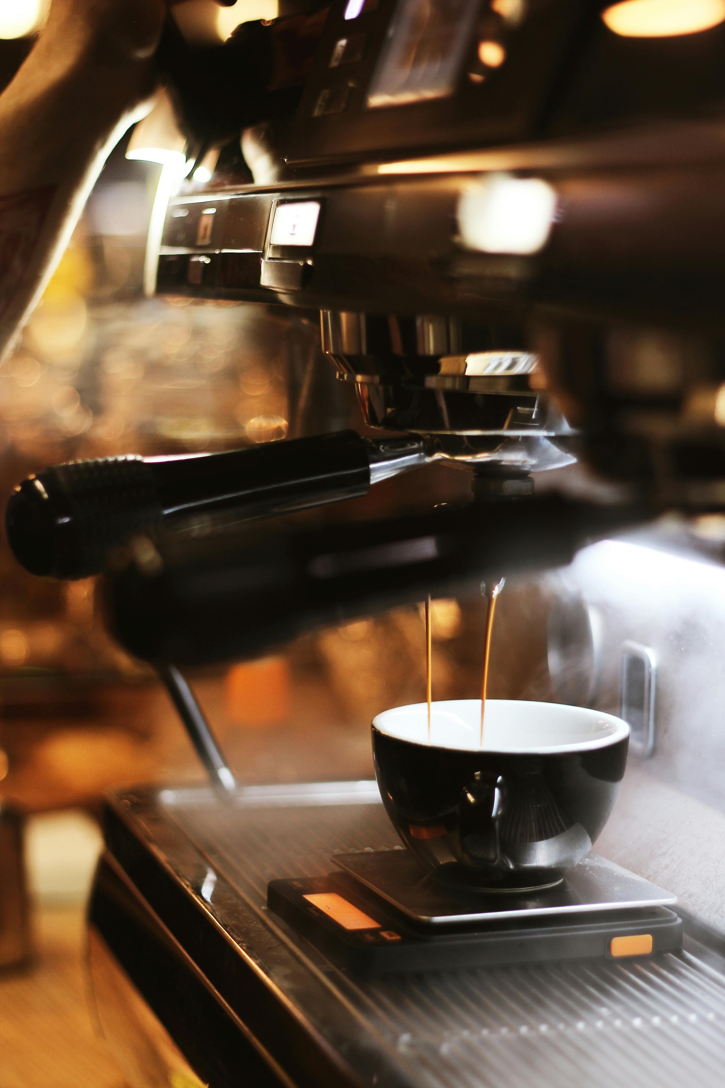 Close-up of an espresso machine pouring coffee into a black and white ceramic cup on a kitchen countertop.