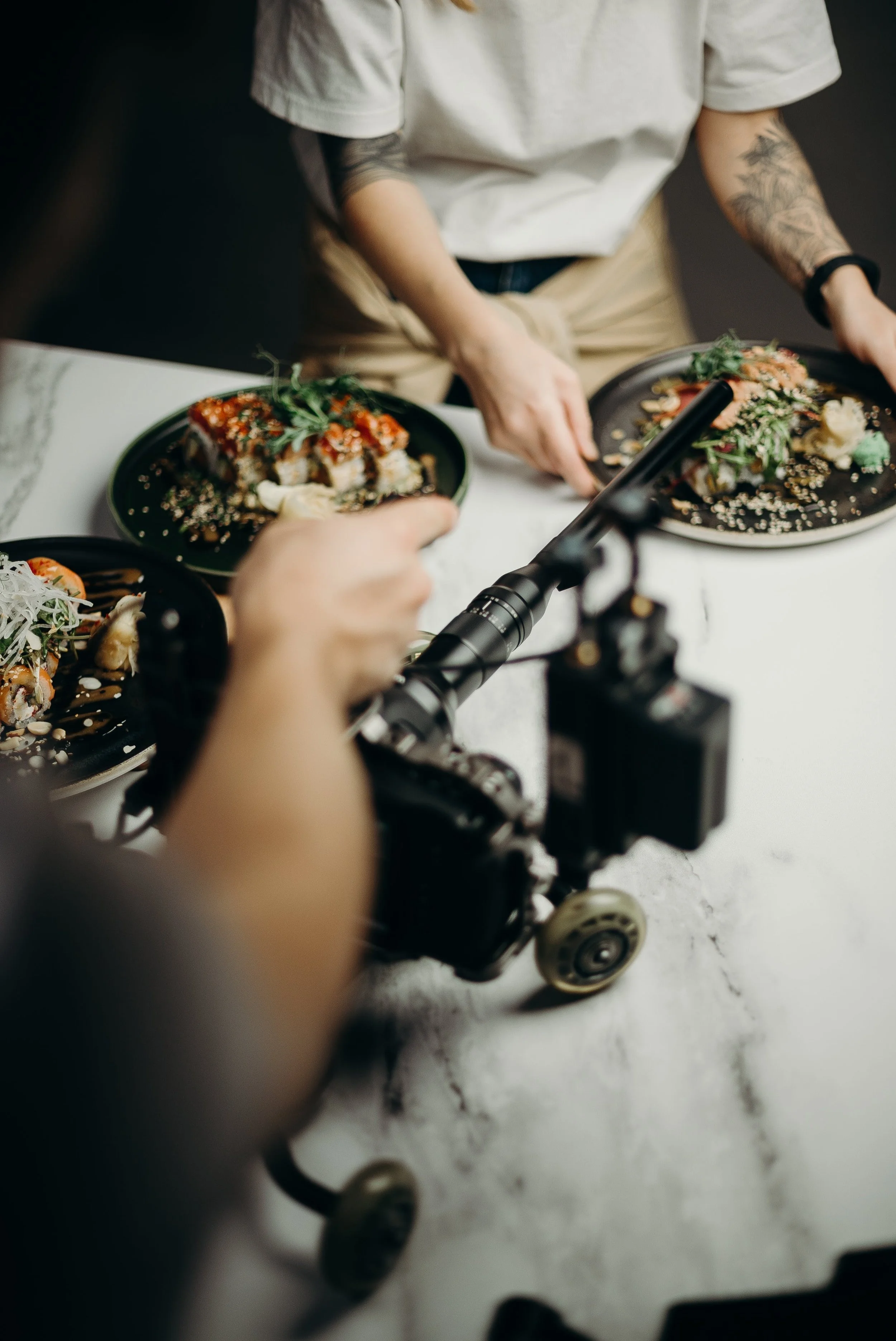 Two people filming a sushi restaurant with a camera on a white table