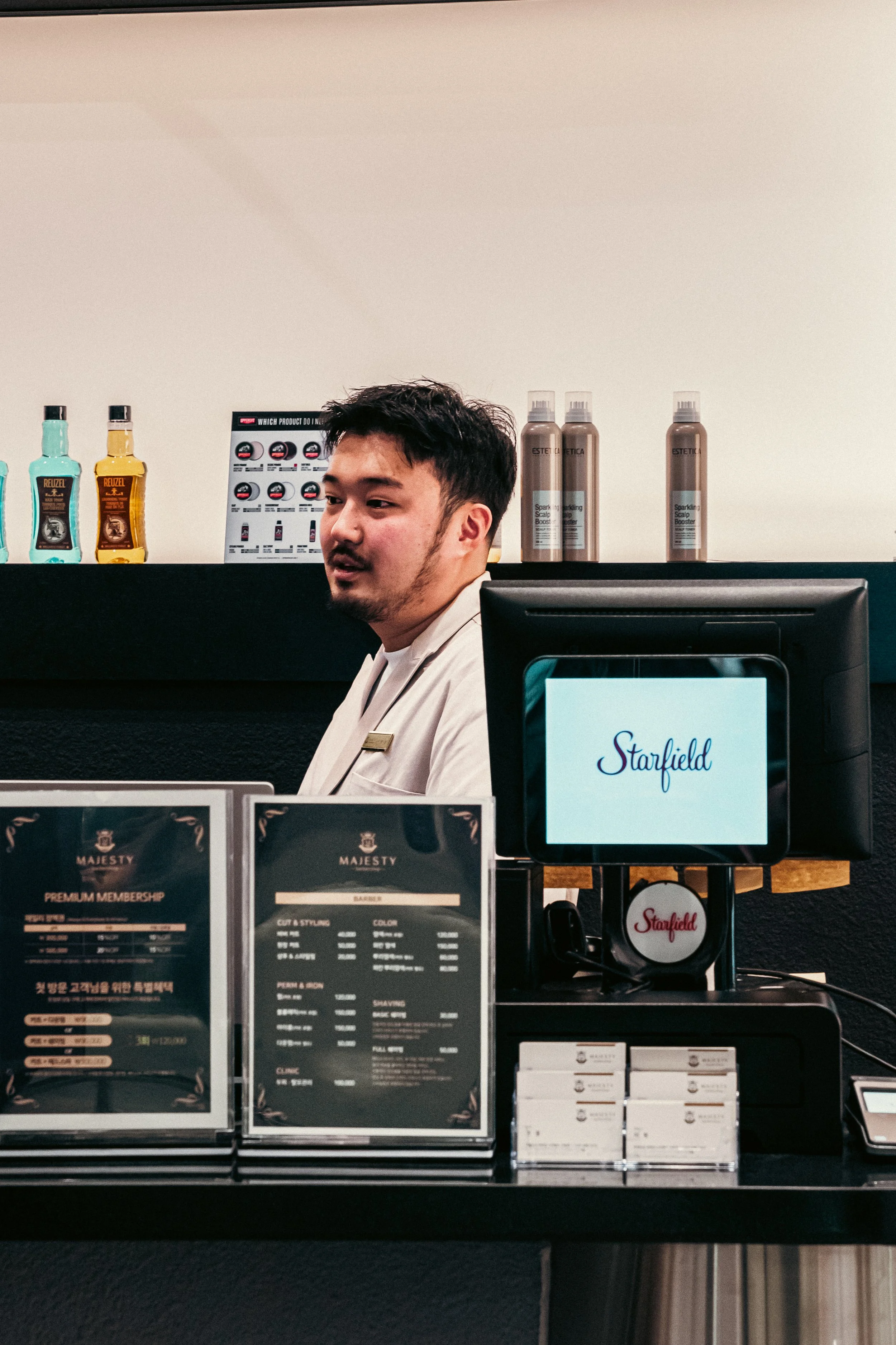 A man working behind a cafe counter, with store signage and product displays visible in the background.
