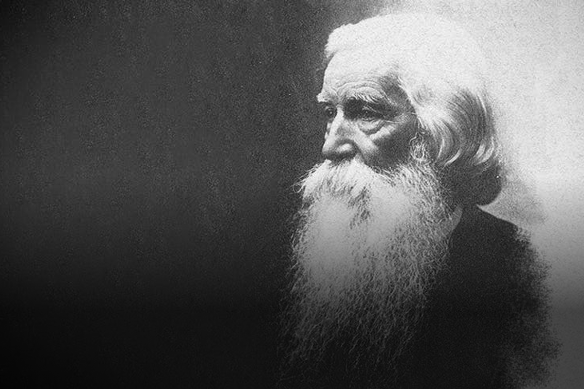Black and white portrait of an elderly man with a long white beard and white hair, looking to the side.