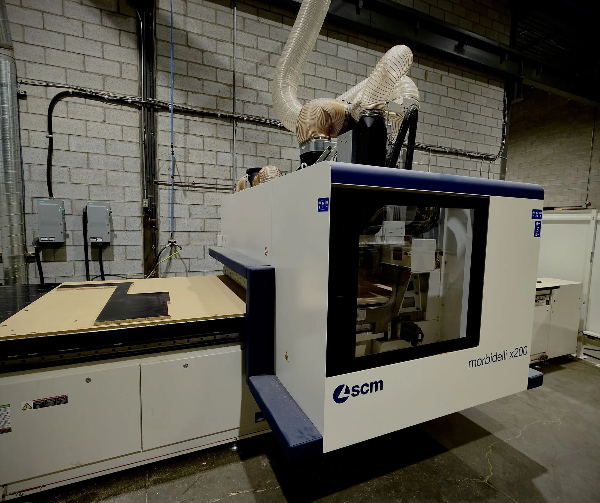 Centre d'usinage CNC Morbidelli x200 de SCM avec système d'aspiration pour la découpe de panneaux de bois dans notre atelier d'ébénisterie à Boisbriand.