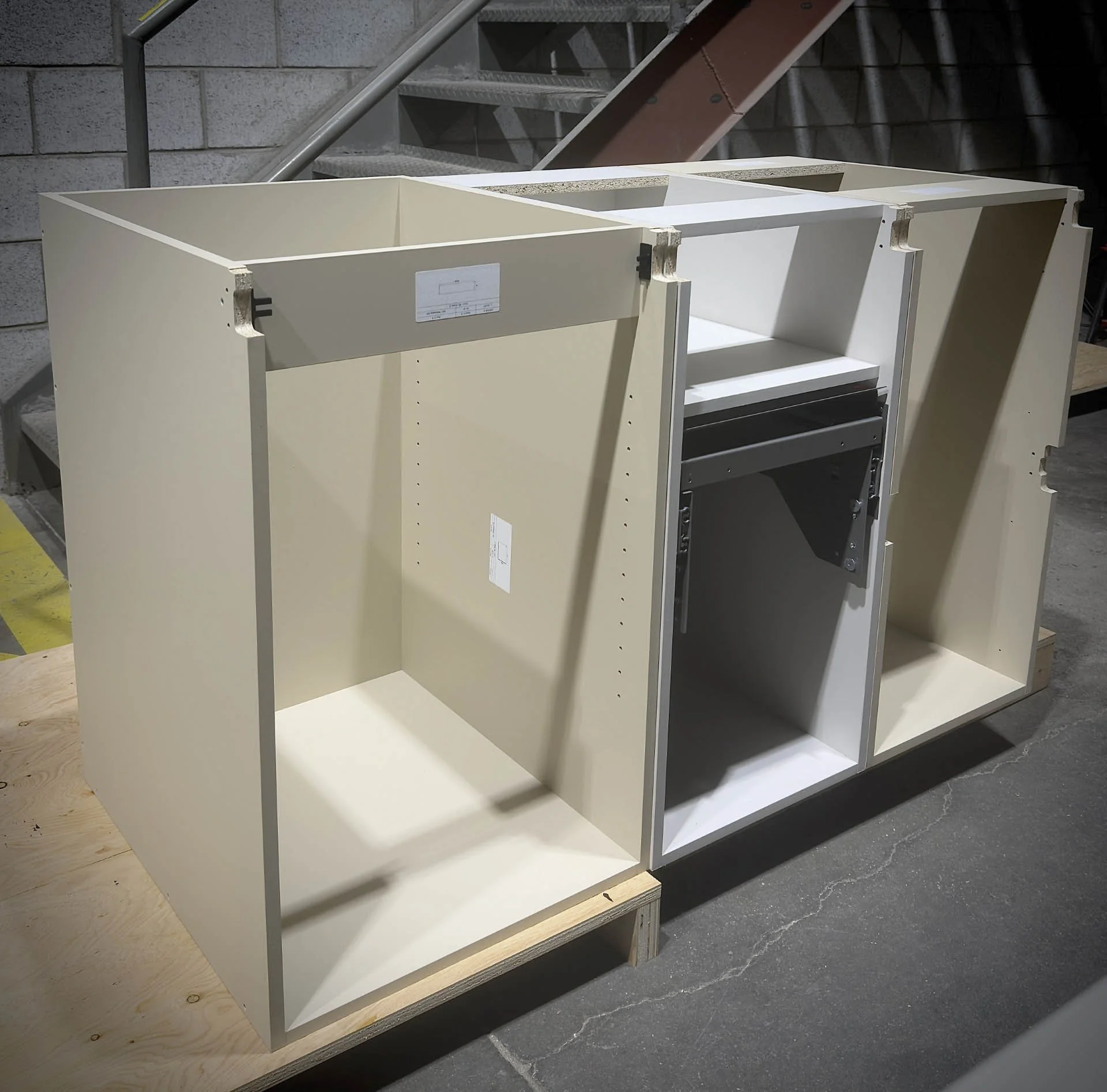 Fabrication en atelier de caissons d'armoires et de modules de cuisine sur mesure en mélanine haut de gamme avec coulisses de tiroirs intégrées pour projet résidentiel à Boisbriand.