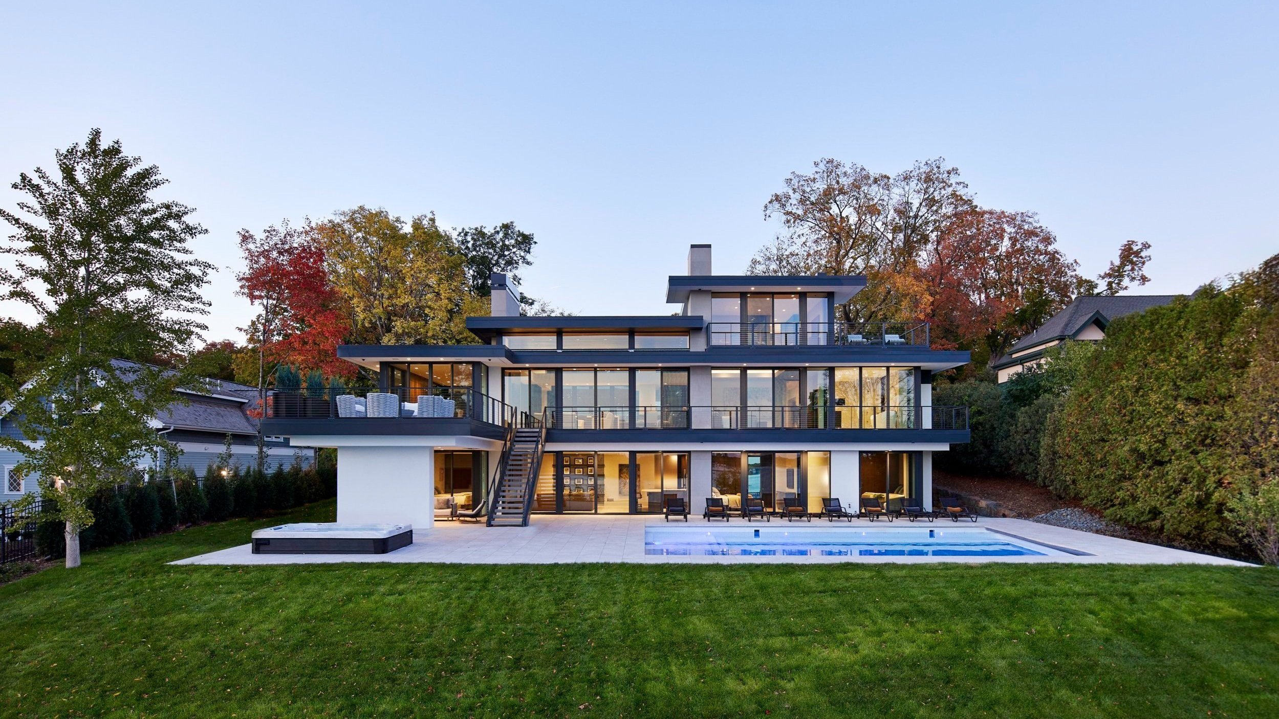 A warm modern home with three levels of floor-to-ceiling windows, a swimming pool, and ample backyard space.