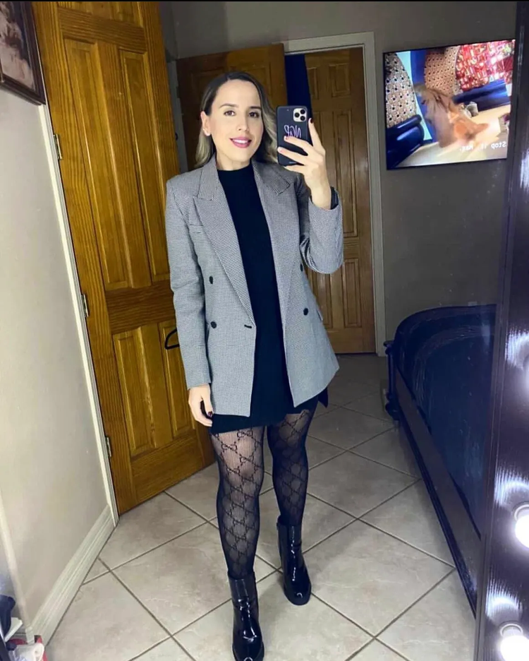 A woman in a grey blazer taking a mirror selfie