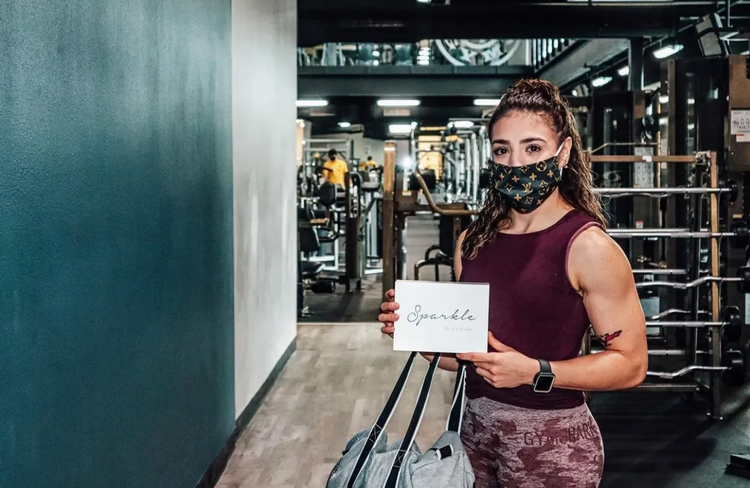 A woman at the gym holding a Sparkle Me White box