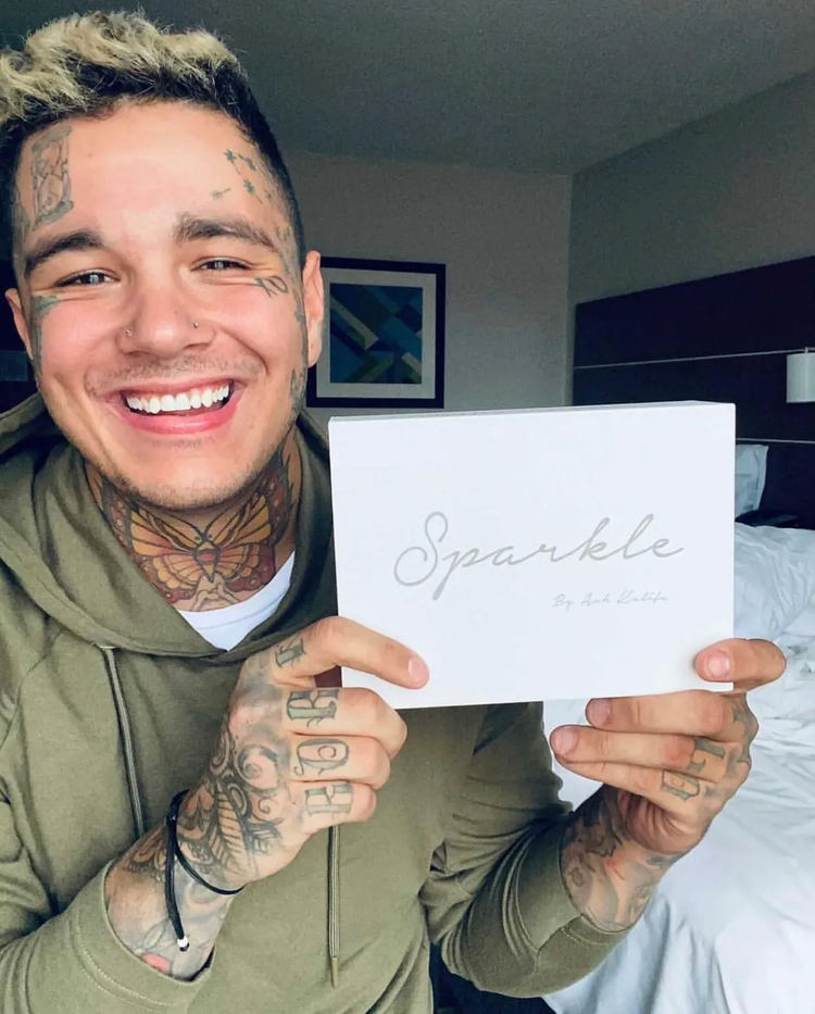 A smiling man holding a white Sparkle Me White box