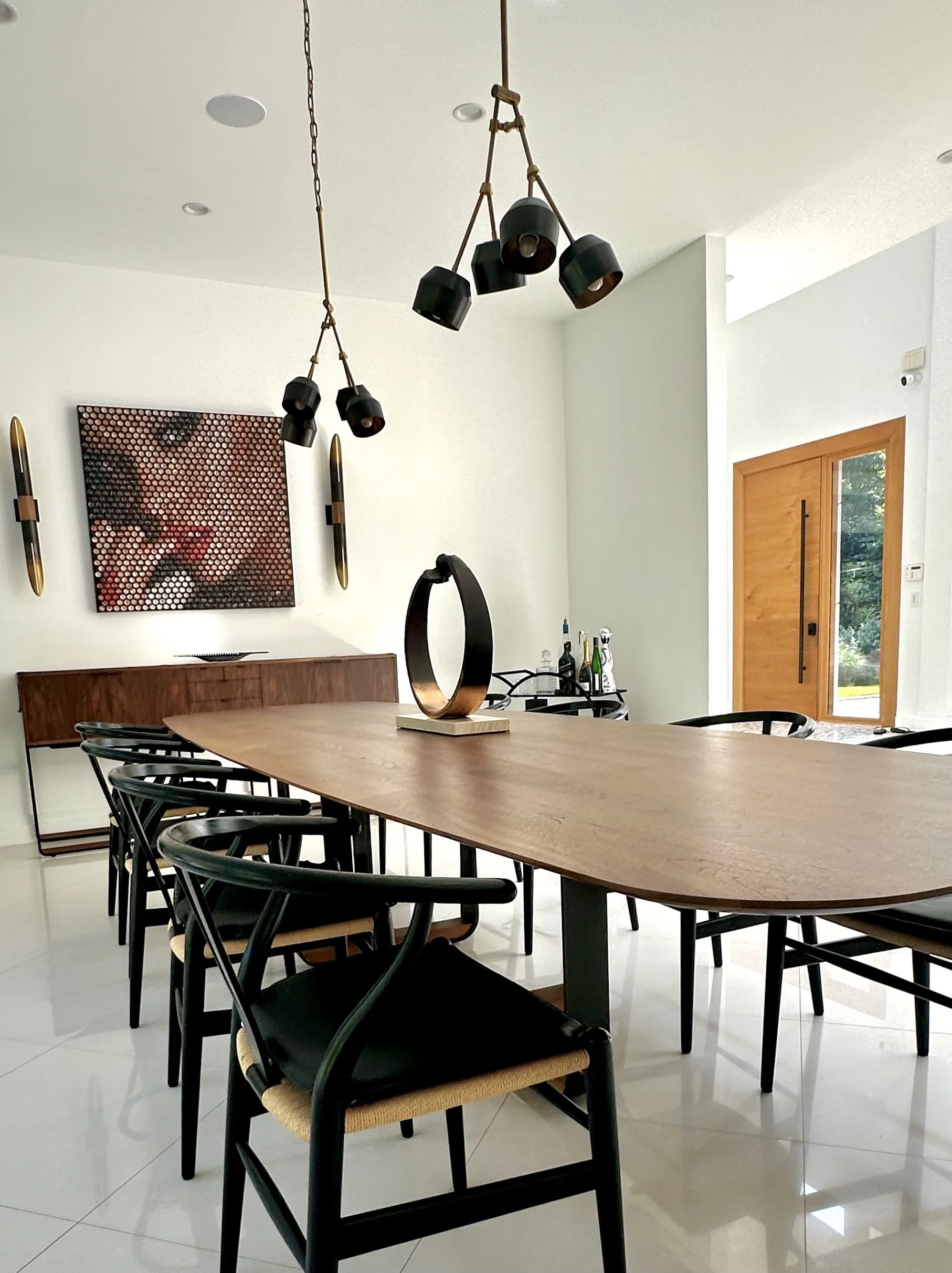 Luxury Dining room, with statement pendants and sconces. Iconic mid century modern wishbone chairs and walnut wood finished table and buffet