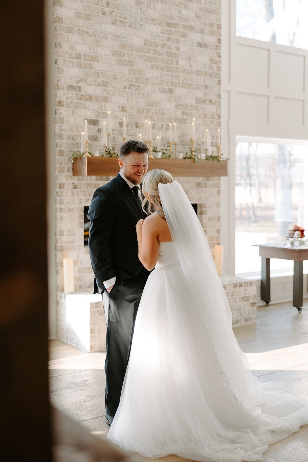 Bride and Groom laughing in front of brick fireplace and milk and honey farms wedding venue in chapmansboro, TN