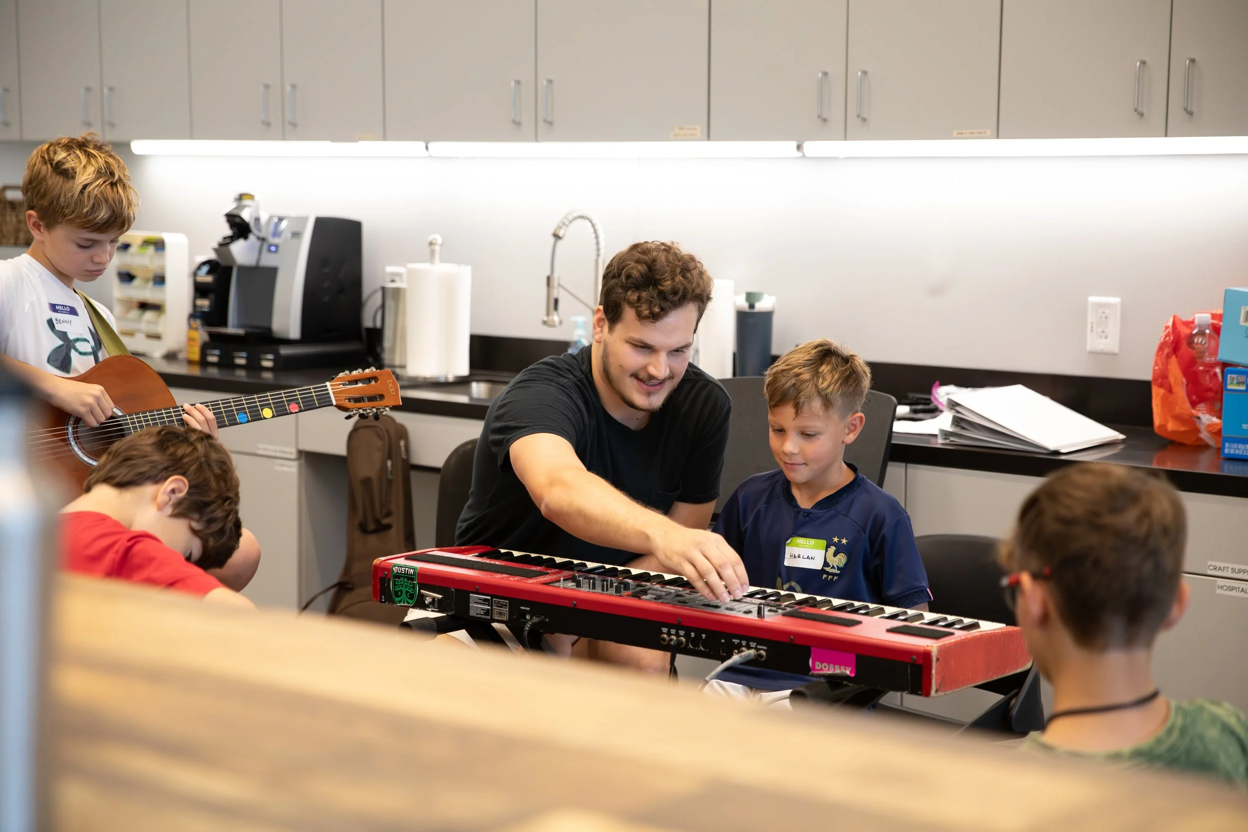 A man teaching children to play musical instruments in a classroom or music room at Summer Camp in Coppell Texas.